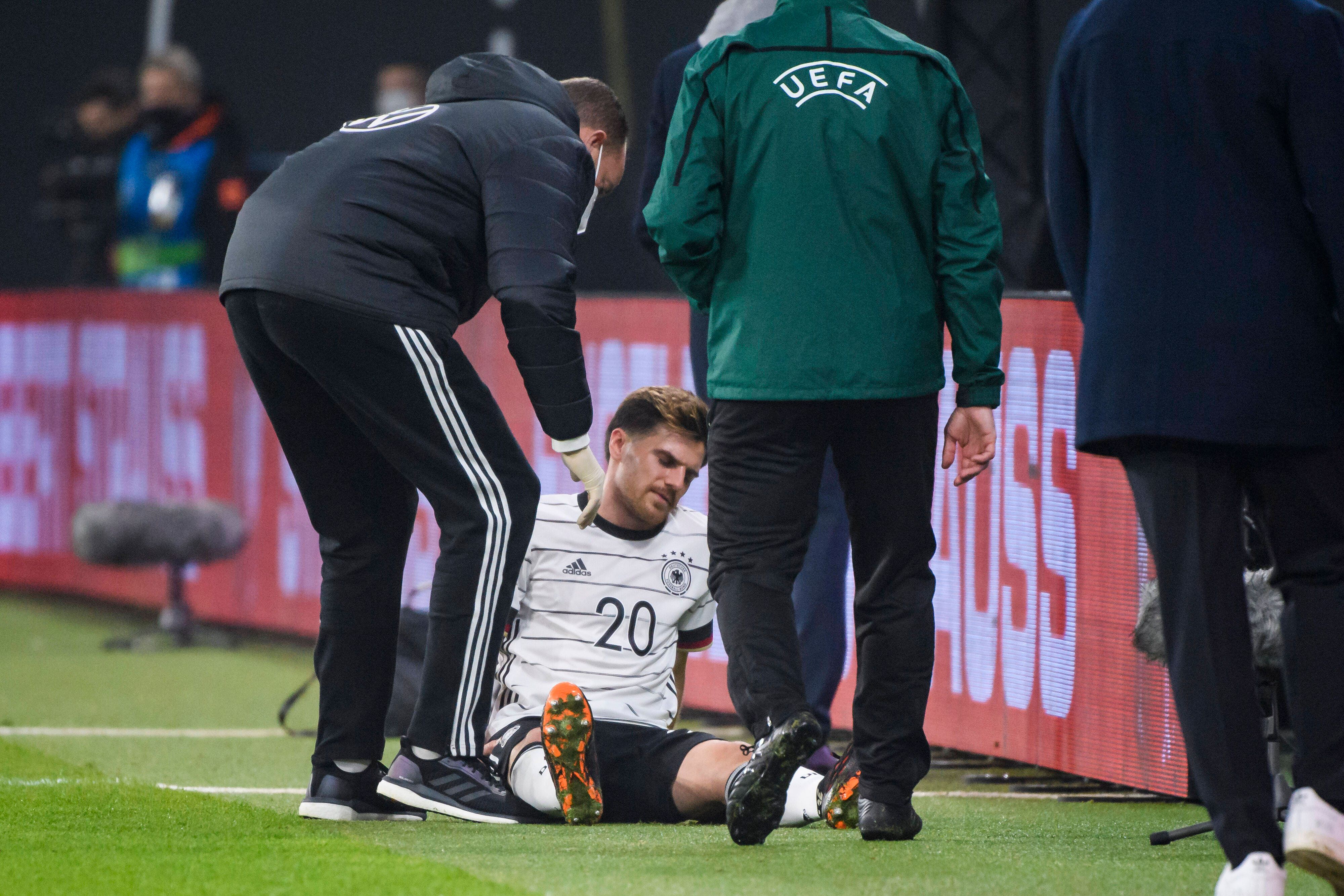 Gladbachs Nationalspieler Jonas Hofmann (M.) sitzt mit einem Muskelbündelriss im rechten Oberschenkel auf dem Rasen der Leipziger Arena und wird von einem Mediziner behandelt.