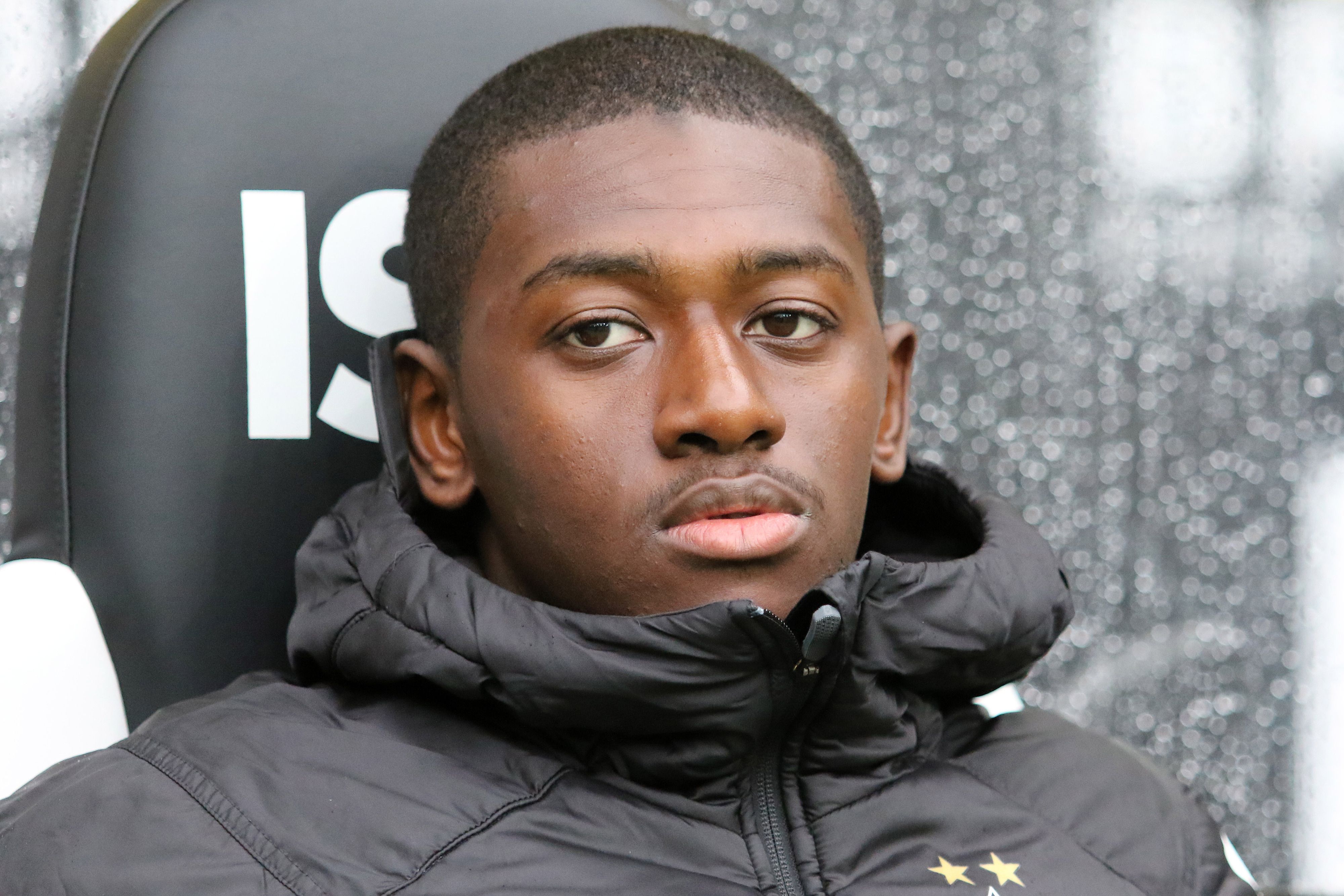 Borussias Abwehrspieler Mamadou Doucouré sitzt auf der Bank und guckt verträumt.
