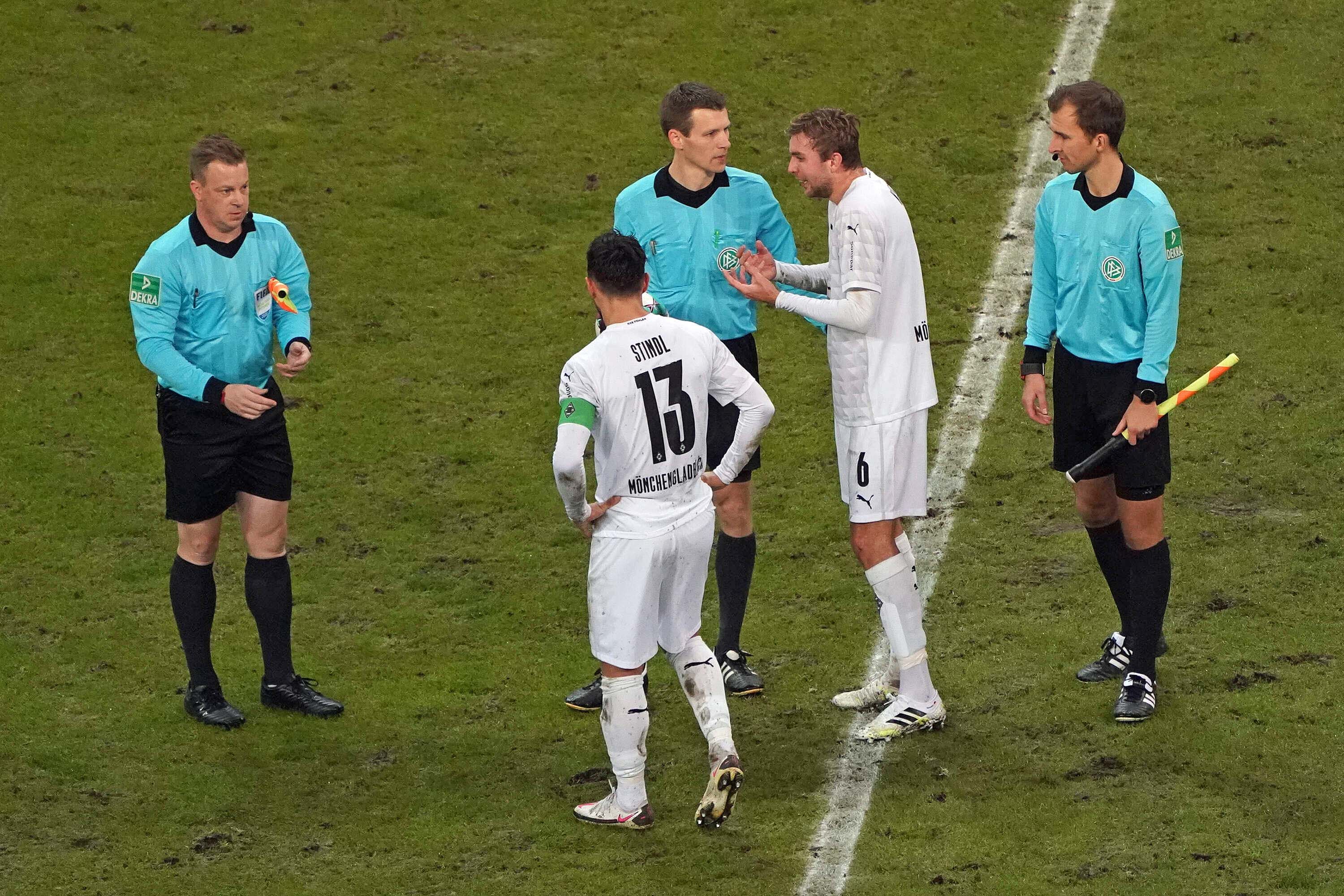 Die Gladbacher Spieler Lars Stindl (mit dem Rücken zur Kamera) und Christoph Kramer (2.v.r.) diskutieren zur Halbzeit mit Schiedsrichter Benjamin Cortus (Mitte).