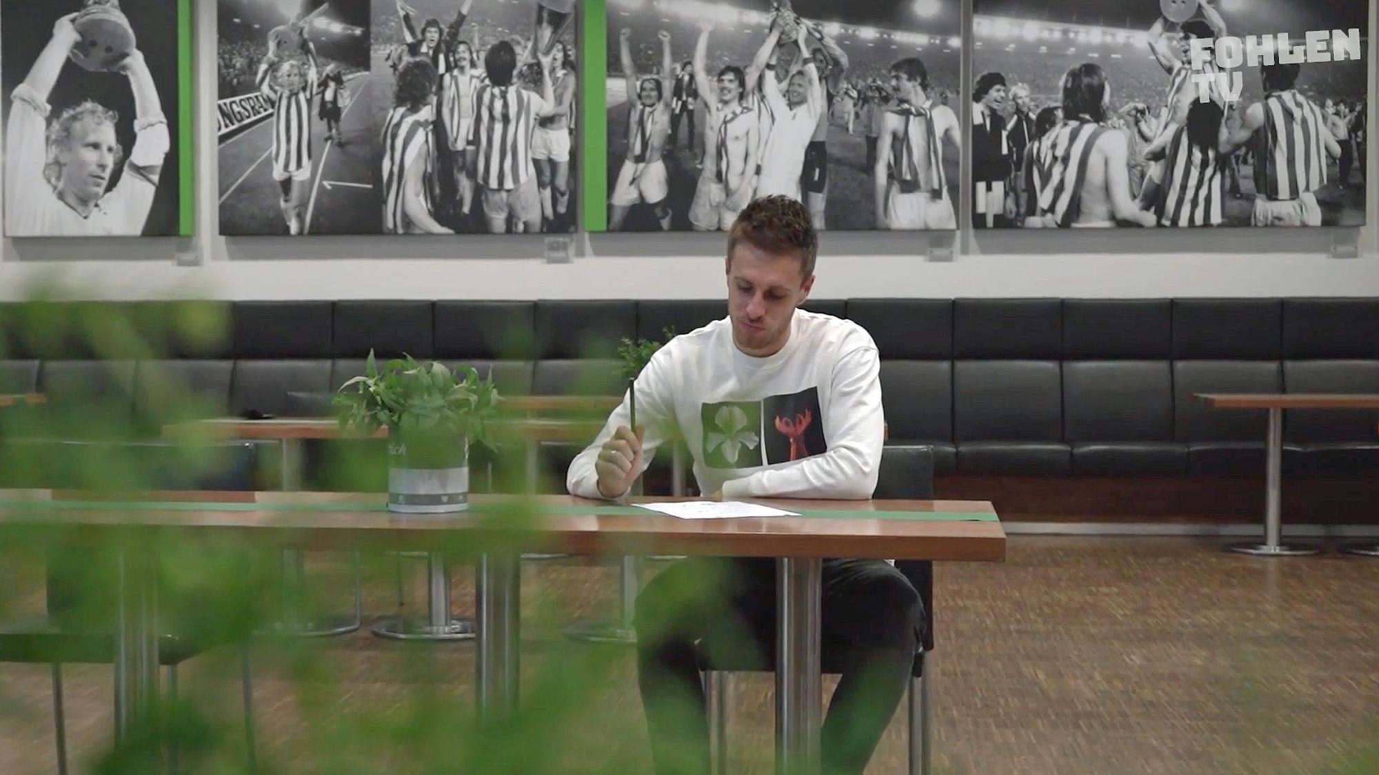 Profispieler Patrick Herrmann sitzt im Business-Bereich des Borussia-Parks und schreibt einen Brief an den Weihnachtsmann.