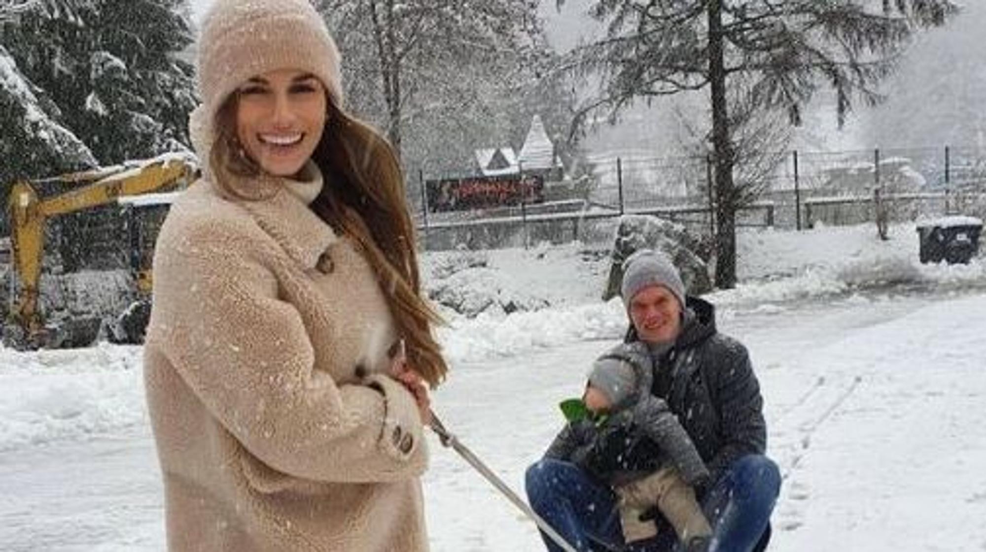 Borussias Abwehrspieler Matthias Ginter (r.) sitzt mit Sohn Matteo auf dem Schlitte, Ehefrau Christina zieht das Gefährt und lacht dabei in die Kamera.