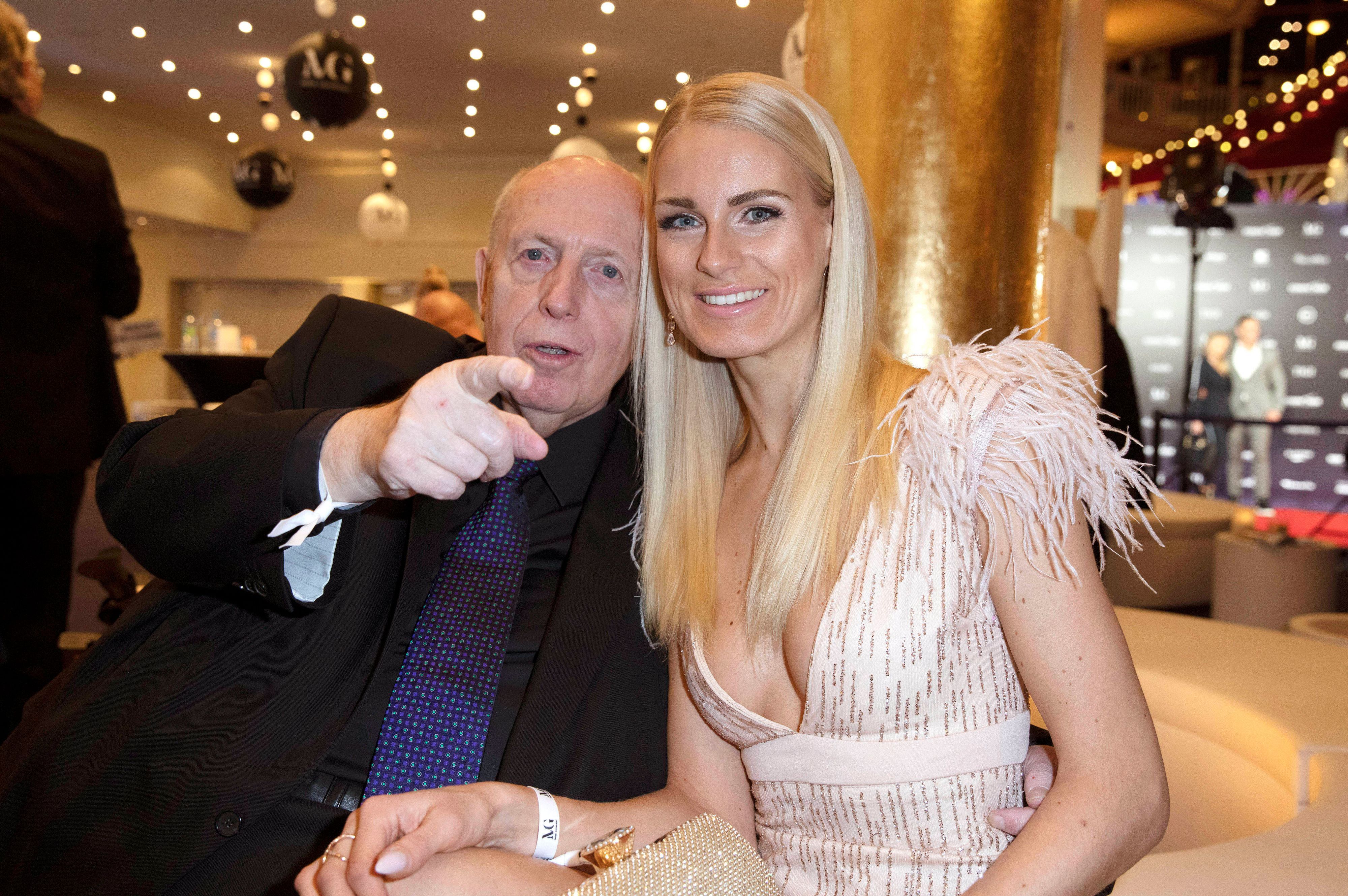 Reiner Calmund zeigt mit dem Finger Richtung Kamera, während er in in der Europa-Park Arena in Rust neben Anne-Kathrin Kosch sitzt.