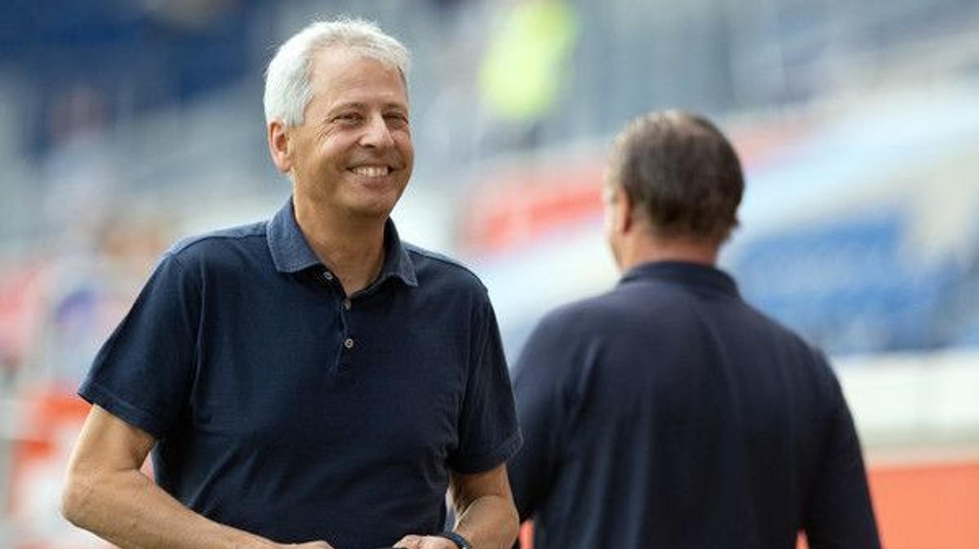 Lucien Favre, Fußballtrainer bei Bundesligist Borussia Dortmund, lächelt nach einem gewonnenen Spiel in die Kamera eines Fotografen.