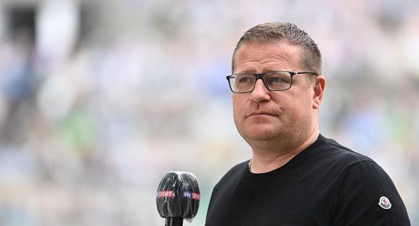 Max Eberl blickt in die Kamera, während ein Mikrofon im entgegengehalten wird.