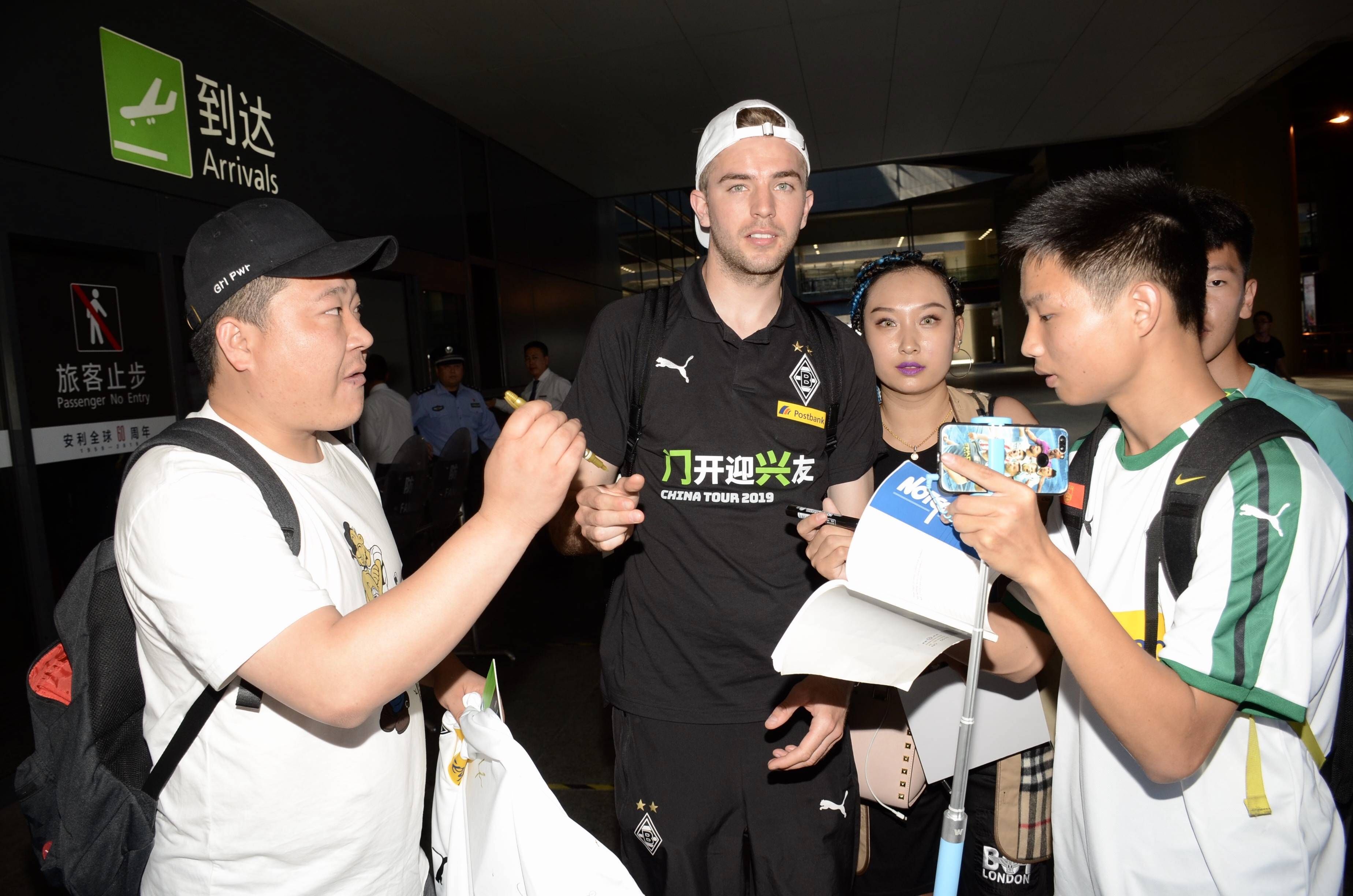 Fußballer Christoph Kramer wird am Flughafen in Shanghai von mehreren Fans umlangert und schreibt Autogramme.