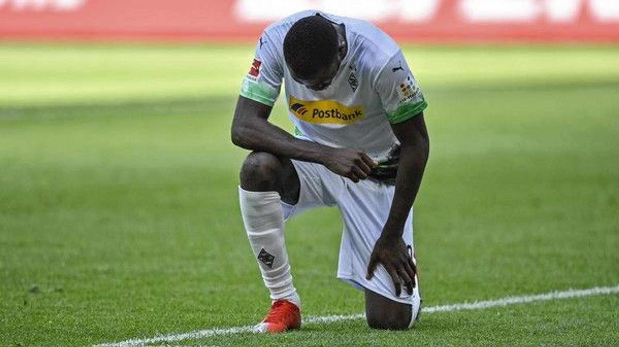 Marcus Thuram, Spieler der Gladbacher Borussia, kniet auf dem Rasen im Borussia-Park.