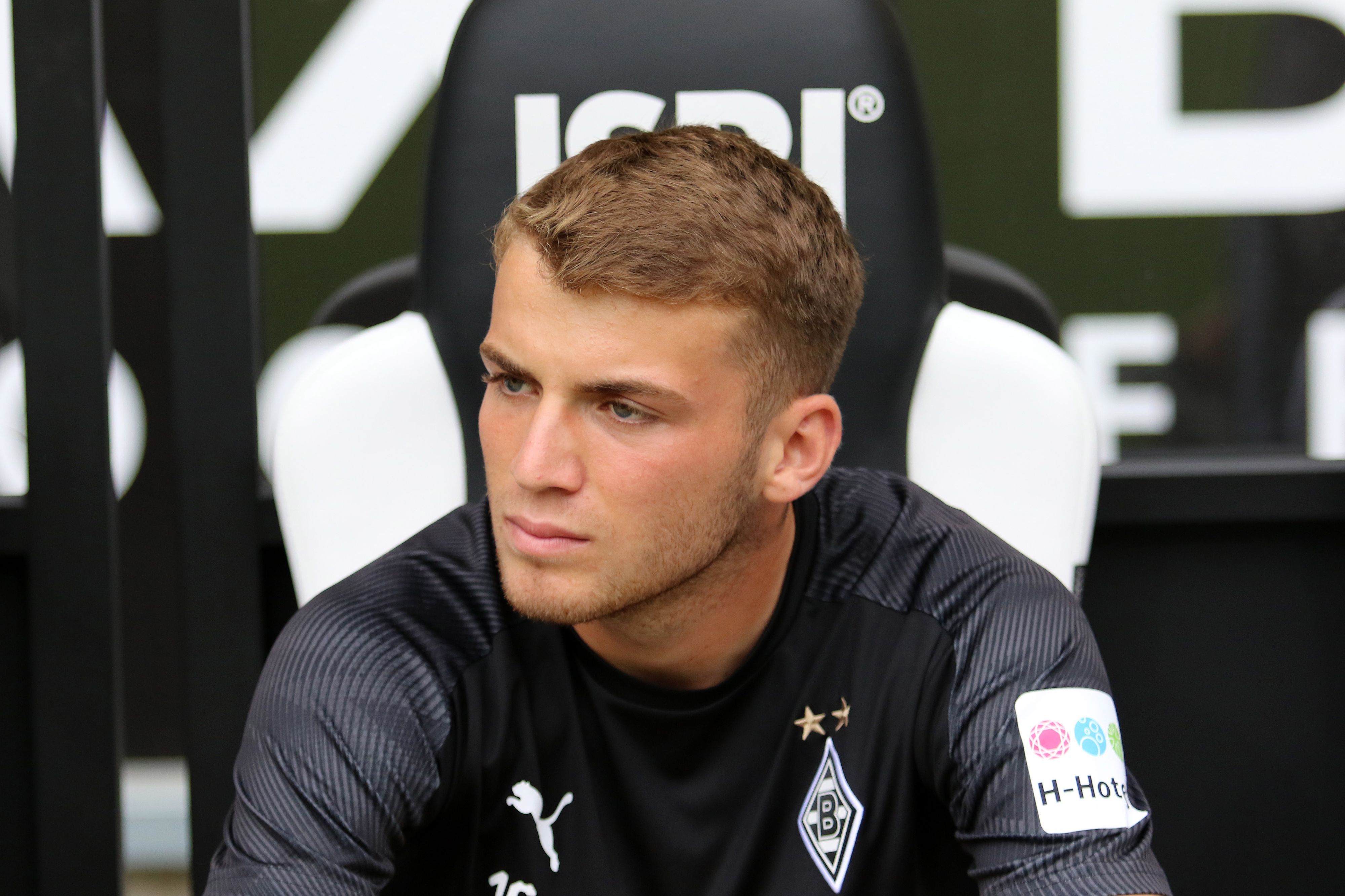 Jodan Beyer, Spieler der Gladbacher Borussia, sitzt auf der Reservebank im Borussia-Park und schaut auf das Spielfeld.