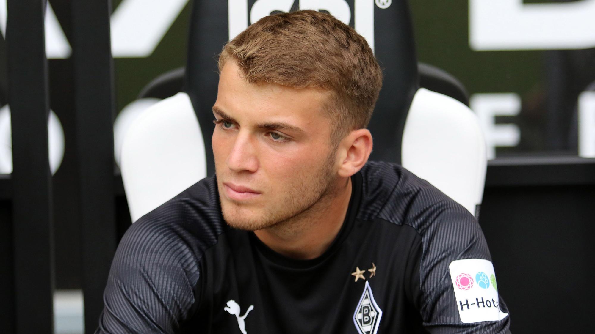 Jodan Beyer, Spieler der Gladbacher Borussia, sitzt auf der Reservebank im Borussia-Park und schaut auf das Spielfeld.