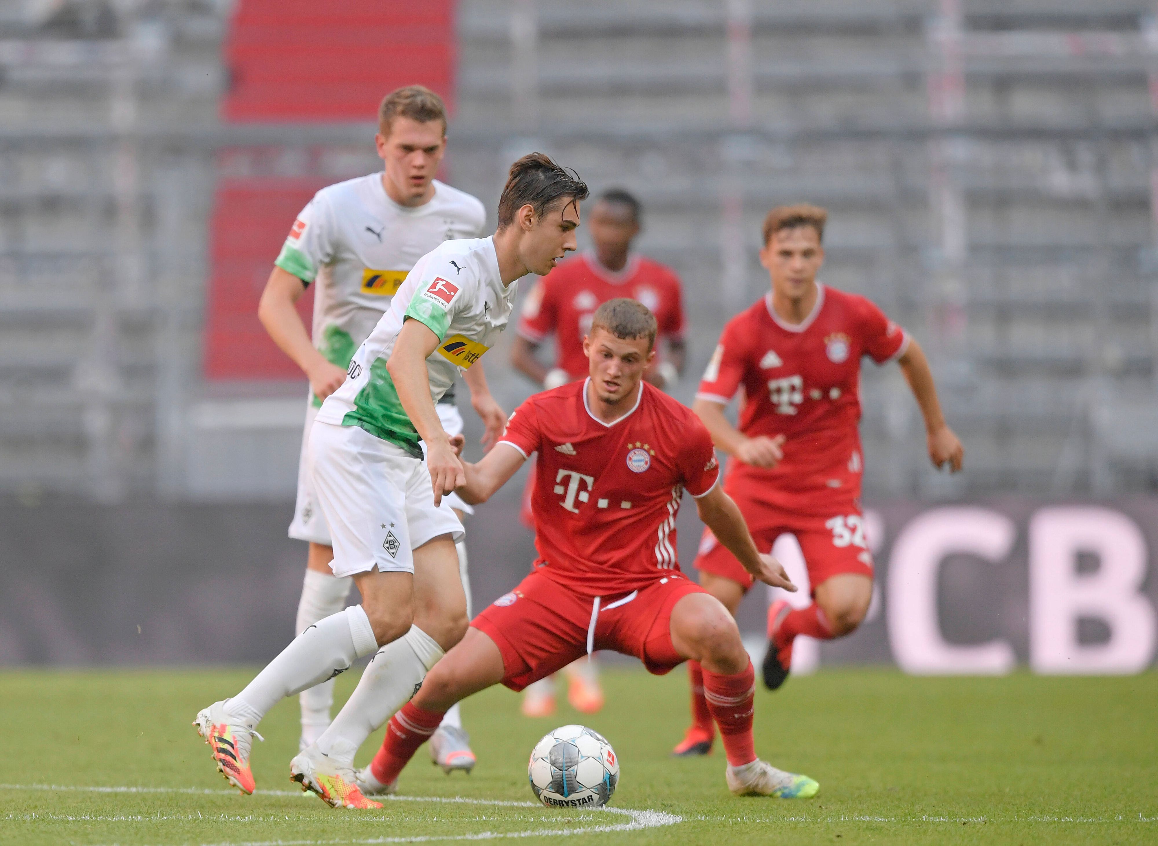 Florian Neuhaus (links) von Borussia Mönchengladbach führt den Ball, Michael Cuisance, im roten Bayern-München-Trikot, möchte ihm diesen abnehmen.