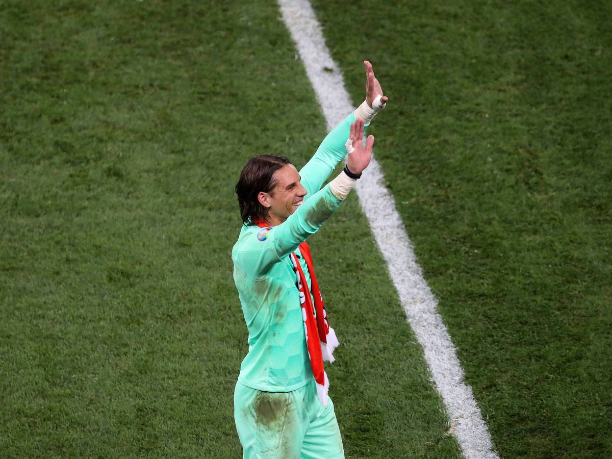 Yann Sommer trägt ein verschmutztes Trikot und hat einen Fan-Schal um den Hals hängen. Seine Arme streckt er in de Himmel und winkt Fans auf der Tribüne zu.