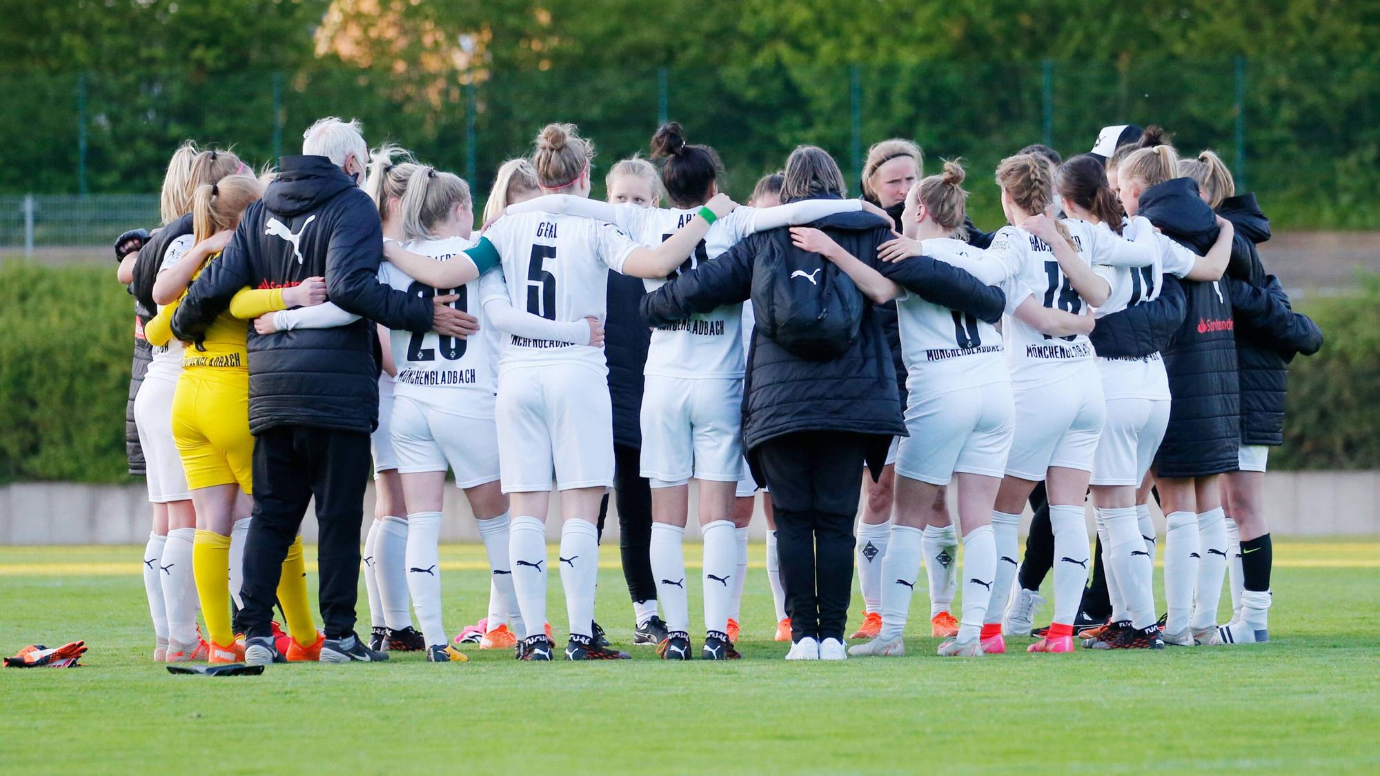 Das Team steht versammelt im Kreis, die Spielerinnen umarmen sich, einige sind nur von hinten zu sehen.
