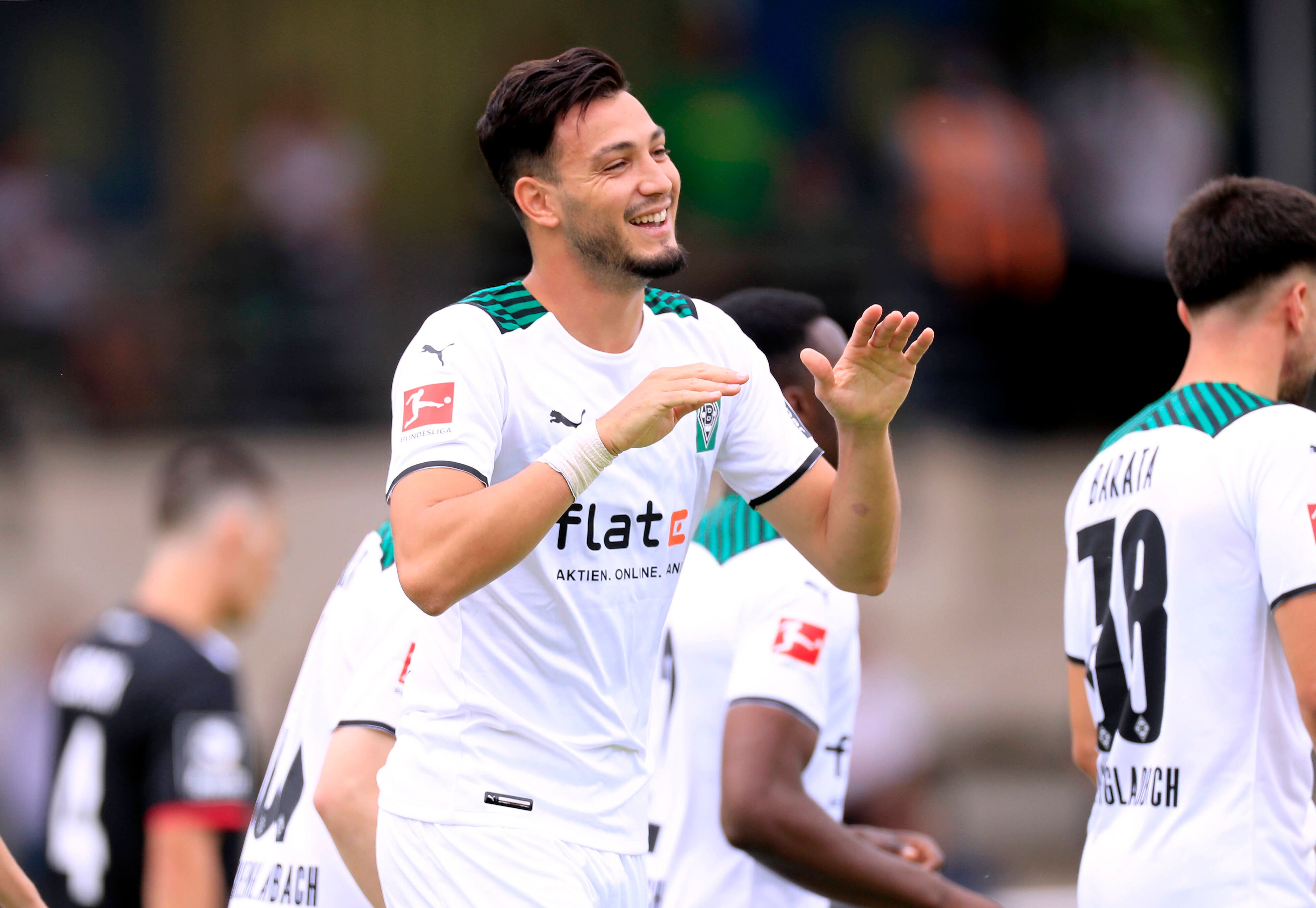Ramy Bensebaini läuft lachend über den Fußballplatz und hält die Hände zum Abschlagen bereit.