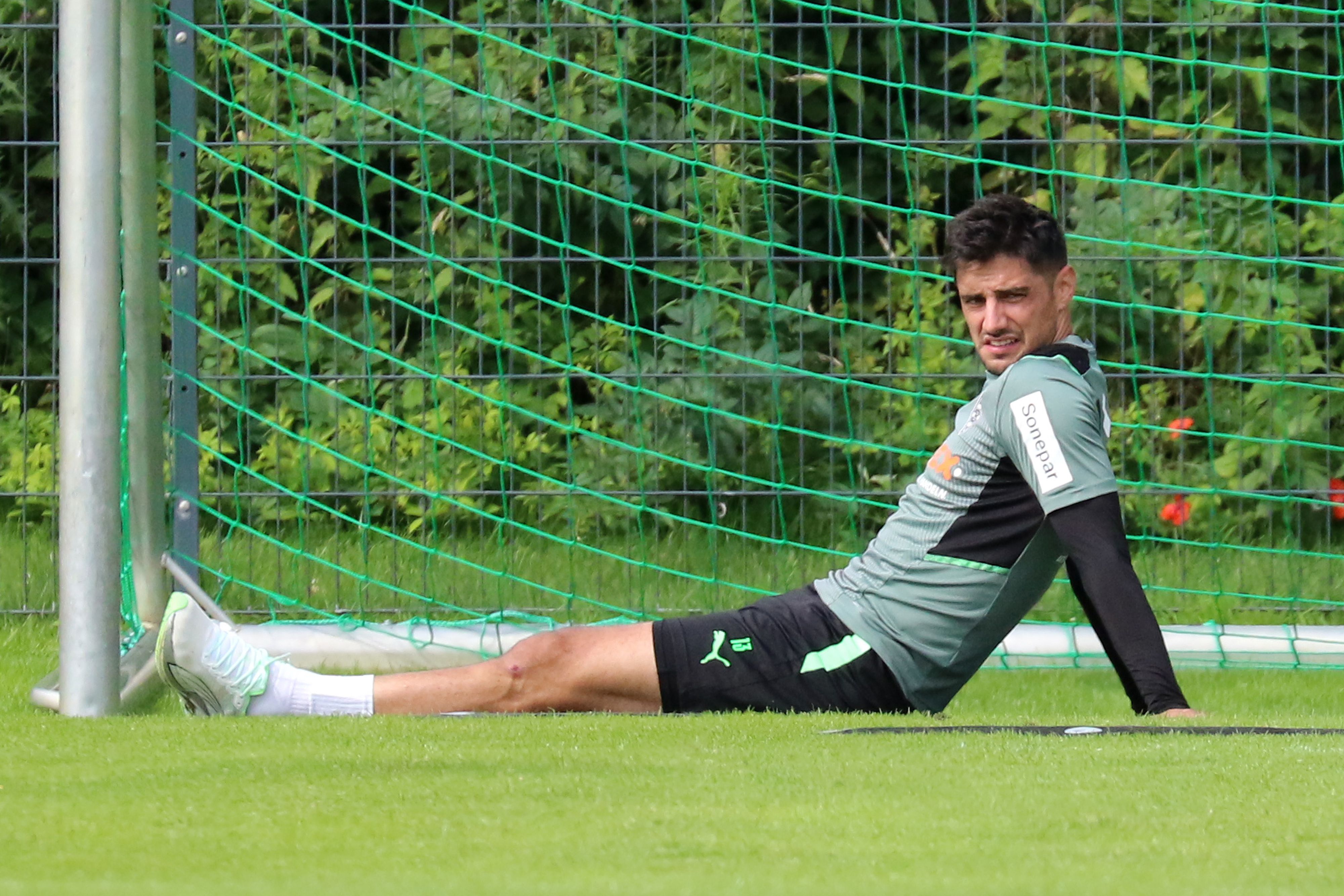 Gladbach-Kapitän Lars Stindl sitzt im Trainingslager in Harsewinkel am 18. Juli 2021 auf dem Rasen und schaut angestrengt.