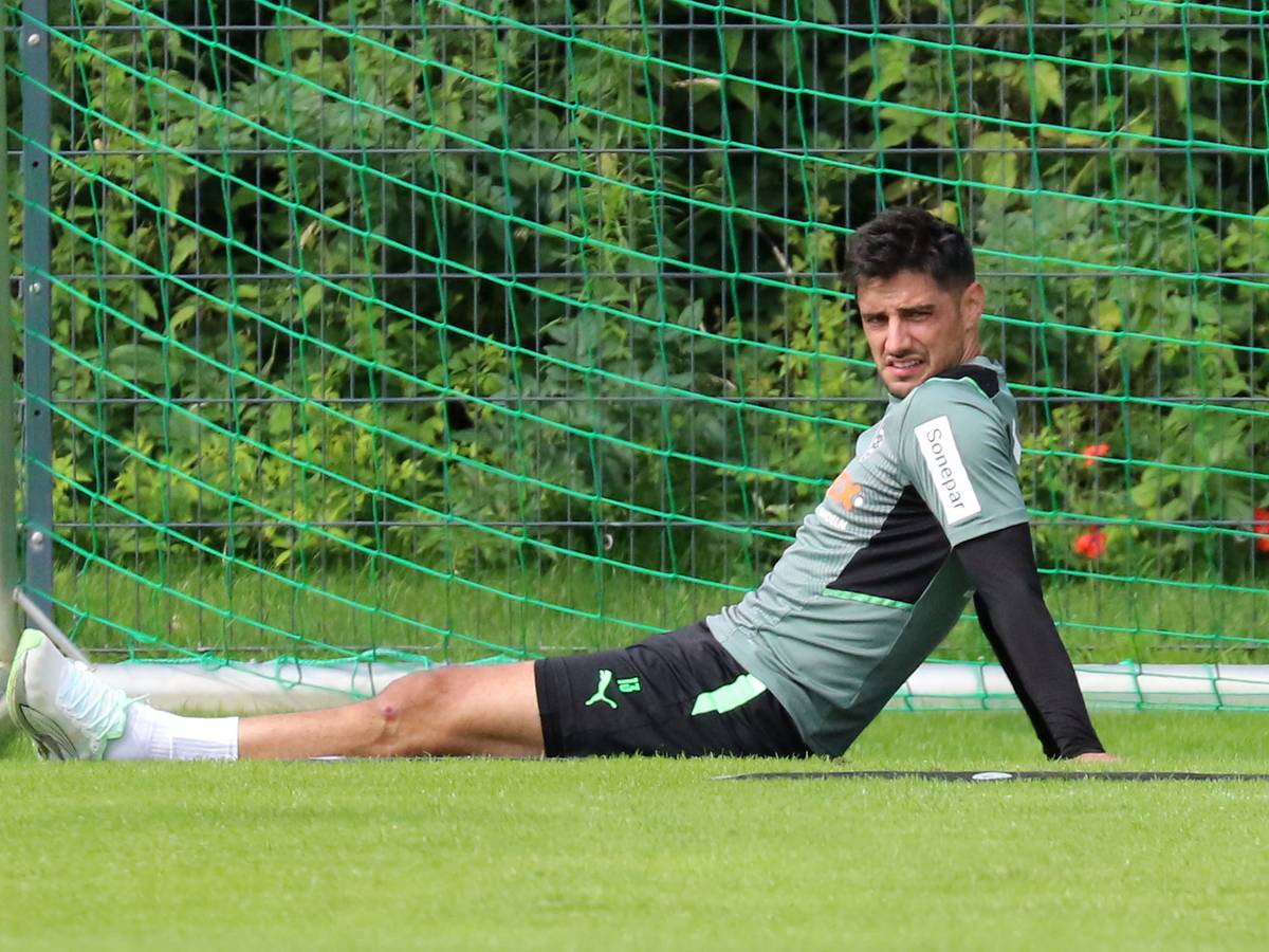 Gladbach-Kapitän Lars Stindl sitzt im Trainingslager in Harsewinkel am 18. Juli 2021 auf dem Rasen und schaut angestrengt.