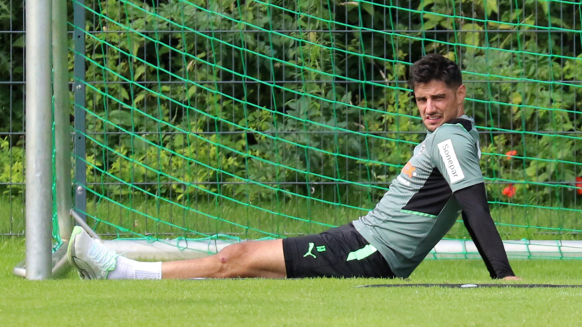 Gladbach-Kapitän Lars Stindl sitzt im Trainingslager in Harsewinkel am 18. Juli 2021 auf dem Rasen und schaut angestrengt.