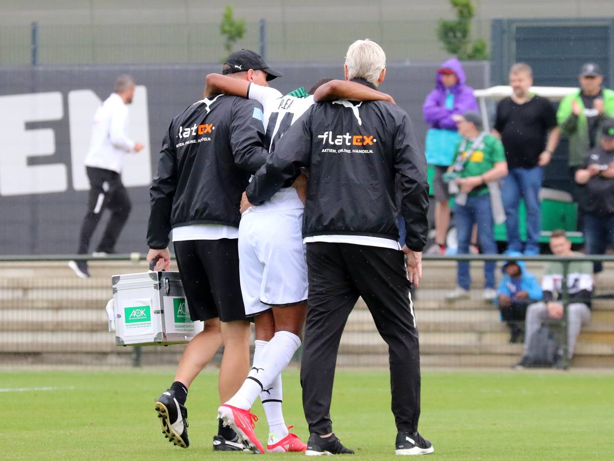 Gladbach-Stürmer Alassane Plea verletzte sich am Samstag (25. Juli 2021) beim Testspiel gegen den FC Metz am Knie und musste das Feld verlassen. Das Foto zeigt ihn humpelnd und gestützt von zwei Borussia-Verantwortlichen.