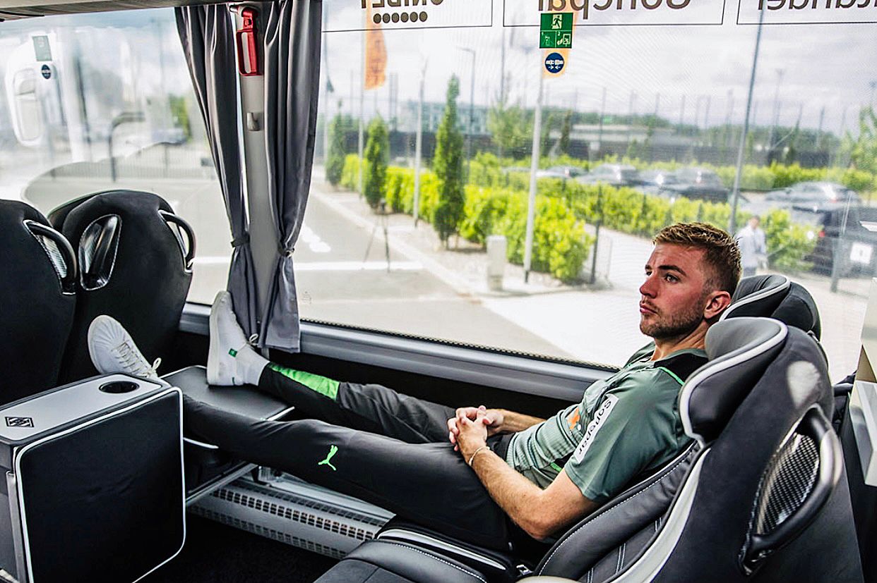 Christoph Kramer sitzt im neuen Mannschaftsbus von Borussia Mönchengladbach. Er hat die Beine hochgelegt und die Hände gefaltet.