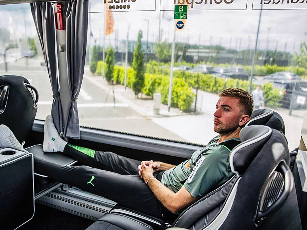 Christoph Kramer sitzt im neuen Mannschaftsbus von Borussia Mönchengladbach. Er hat die Beine hochgelegt und die Hände gefaltet.