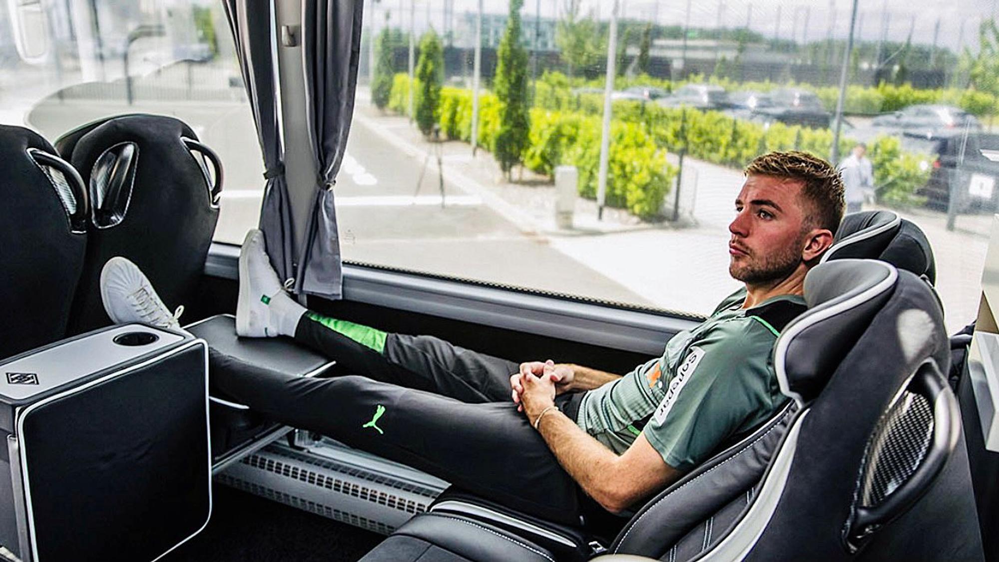 Christoph Kramer sitzt im neuen Mannschaftsbus von Borussia Mönchengladbach. Er hat die Beine hochgelegt und die Hände gefaltet.