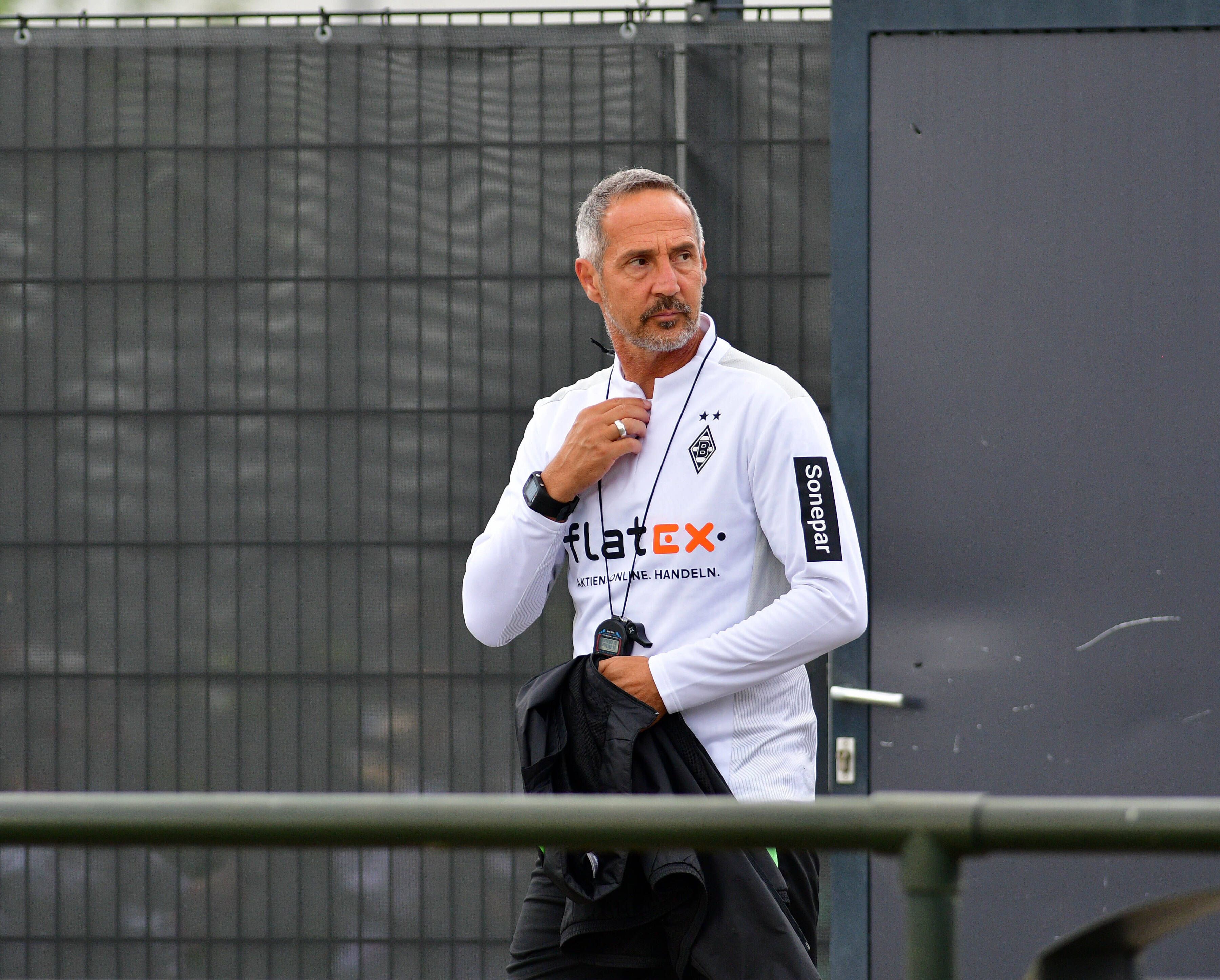 Gladbachs neuer Cheftrainer Adi Hütter betritt das Trainingsgelände im Borussia-Park, er fasst sich dabei mit der rechten Hand an den Hals.
