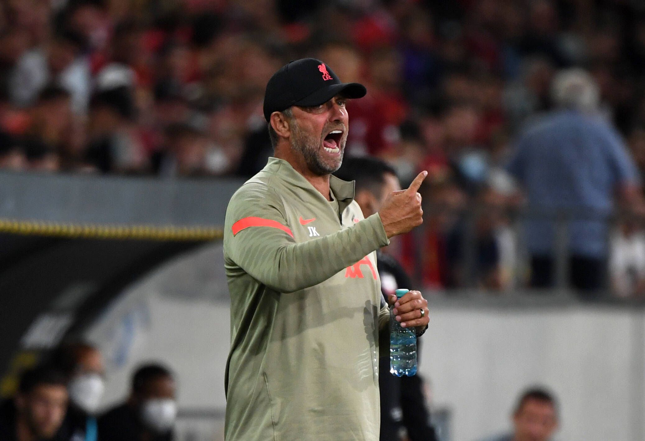 Jürgen Klopp, Trainer des englischen Top-Klubs FC Liverpool, brüllt bei einem Testspiel gegen Hertha BSC in Innsbruck am 29. Juli 2021 Anweisungen auf das Spielfeld. Mit dem rechten Arm gestikuliert er, in der linken Hand hält er derweil eine Getränkeflasche.