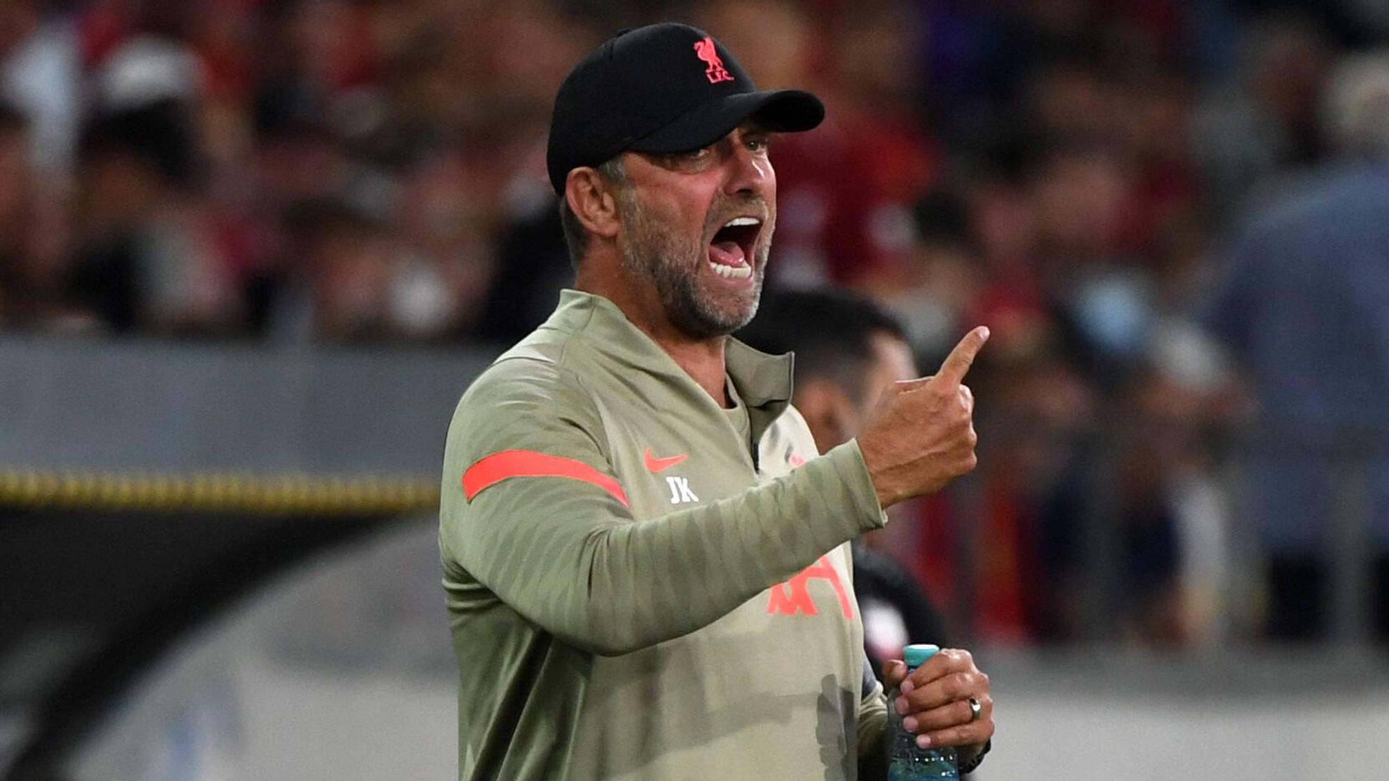 Jürgen Klopp, Trainer des englischen Top-Klubs FC Liverpool, brüllt bei einem Testspiel gegen Hertha BSC in Innsbruck am 29. Juli 2021 Anweisungen auf das Spielfeld. Mit dem rechten Arm gestikuliert er, in der linken Hand hält er derweil eine Getränkeflasche.