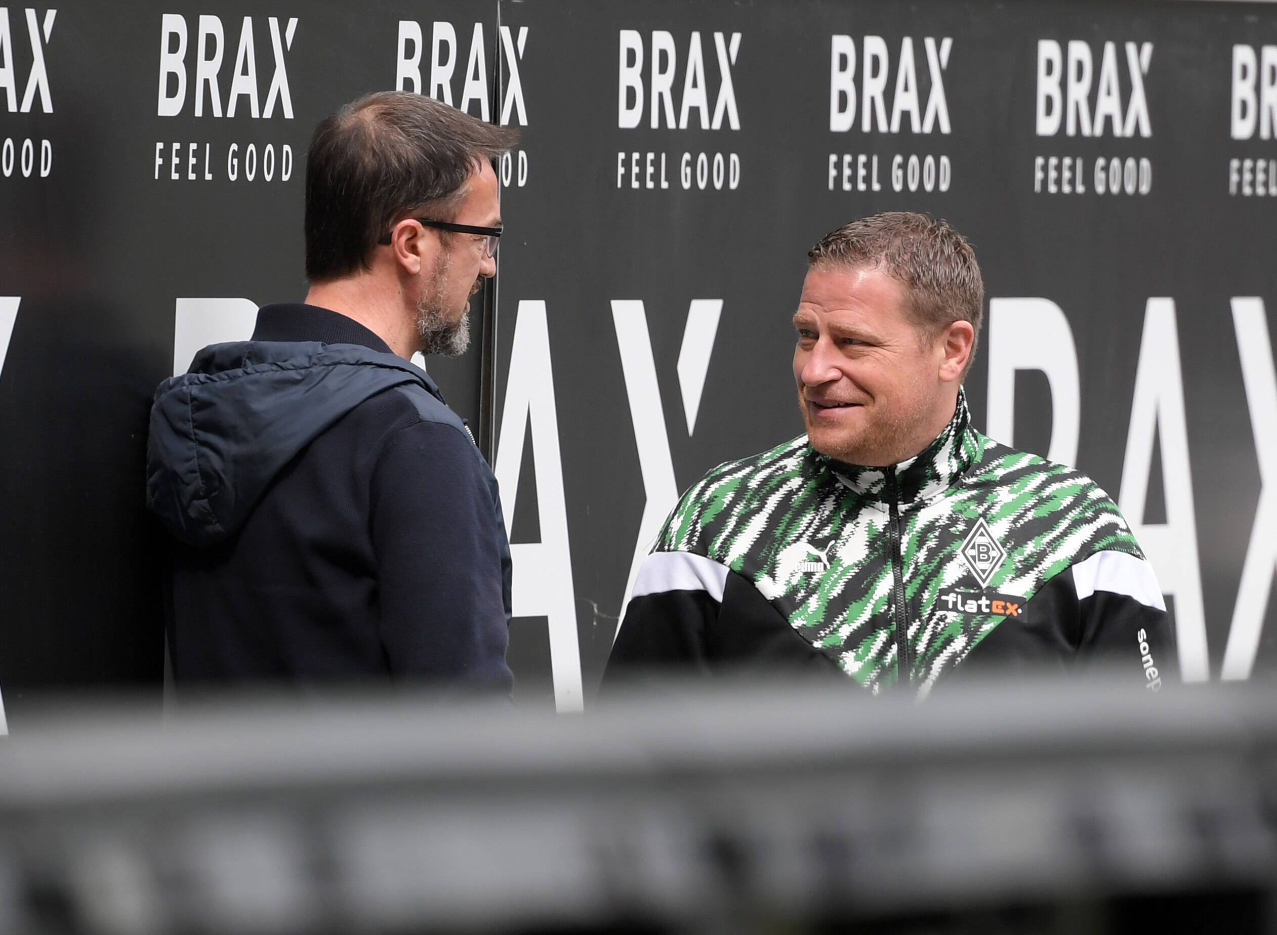 Gladbachs Manager Max Eberl (r.) unterhält sich am 17. April 2021 im Borussia-Park am Spielfeldrand mit Fredi Bobic (l.). Beide lächeln dabei.