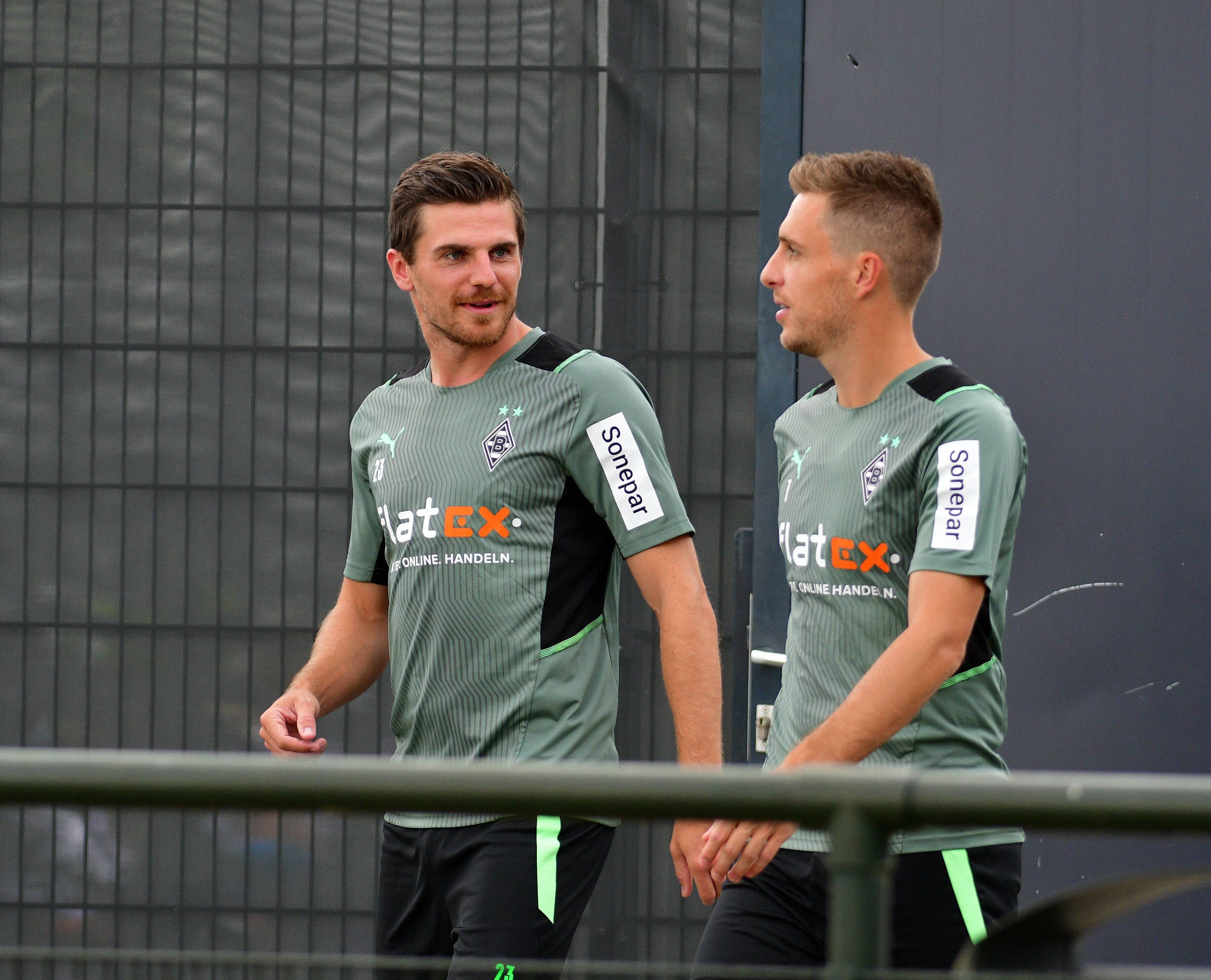 Gladbachs Nationalspieler Jonas Hofmann (links) betritt gemeinsam mit Team-Kollege Patrick Herrmann (rechts) am 27. Juli 2021 das Trainingsgelände im Borussia-Park. Die beiden unterhalten sich dabei, Hofmann schaut zu Herrmann rüber.