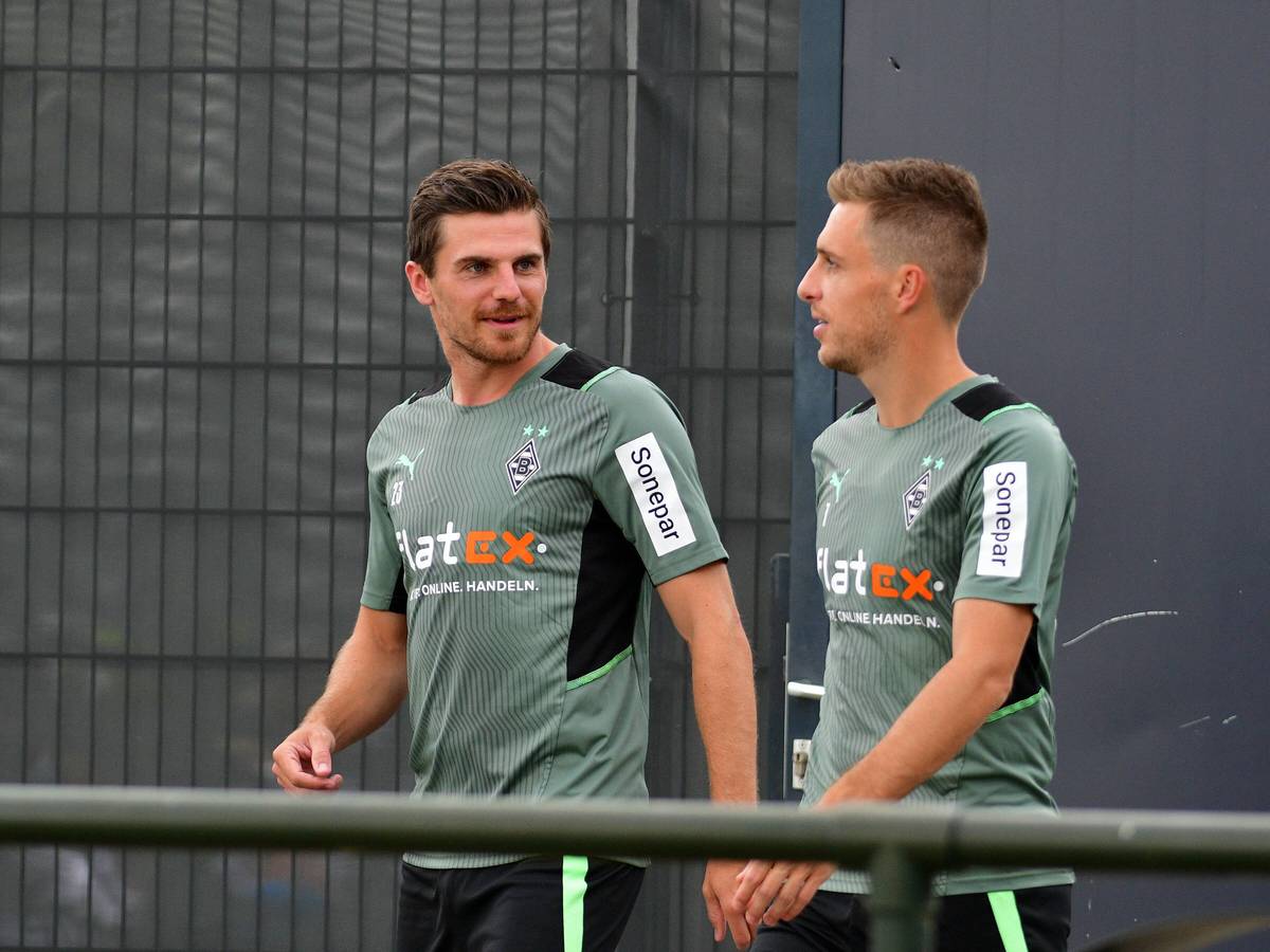 Gladbachs Nationalspieler Jonas Hofmann (links) betritt gemeinsam mit Team-Kollege Patrick Herrmann (rechts) am 27. Juli 2021 das Trainingsgelände im Borussia-Park. Die beiden unterhalten sich dabei, Hofmann schaut zu Herrmann rüber.