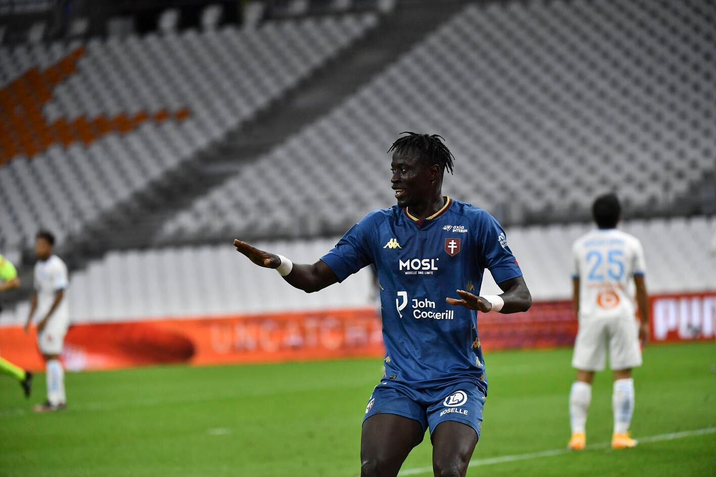 Ibrahima Niane im blauen Trikot des FC Metz mit angewinkelten Armen in einer Jubelpose und dem Blick zur Seite.