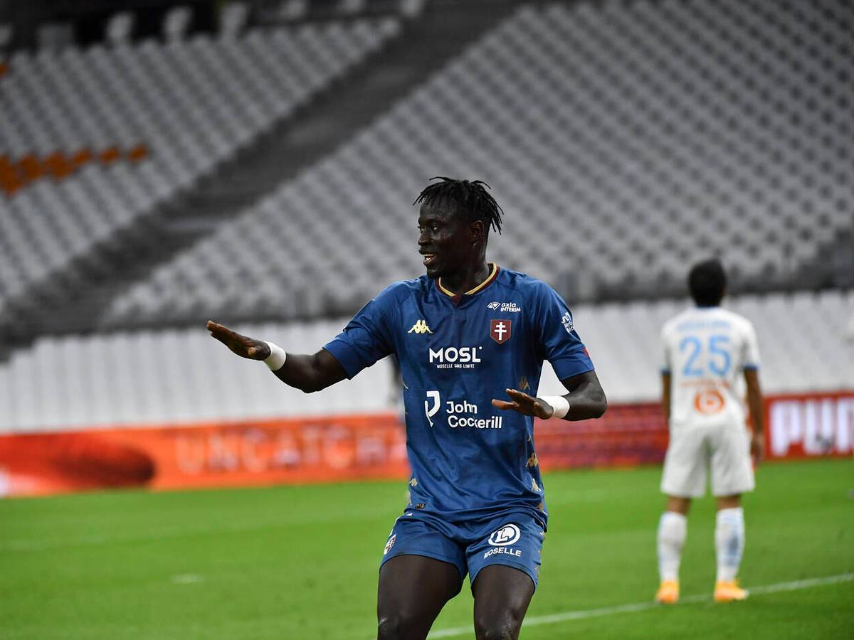 Ibrahima Niane im blauen Trikot des FC Metz mit angewinkelten Armen in einer Jubelpose und dem Blick zur Seite.