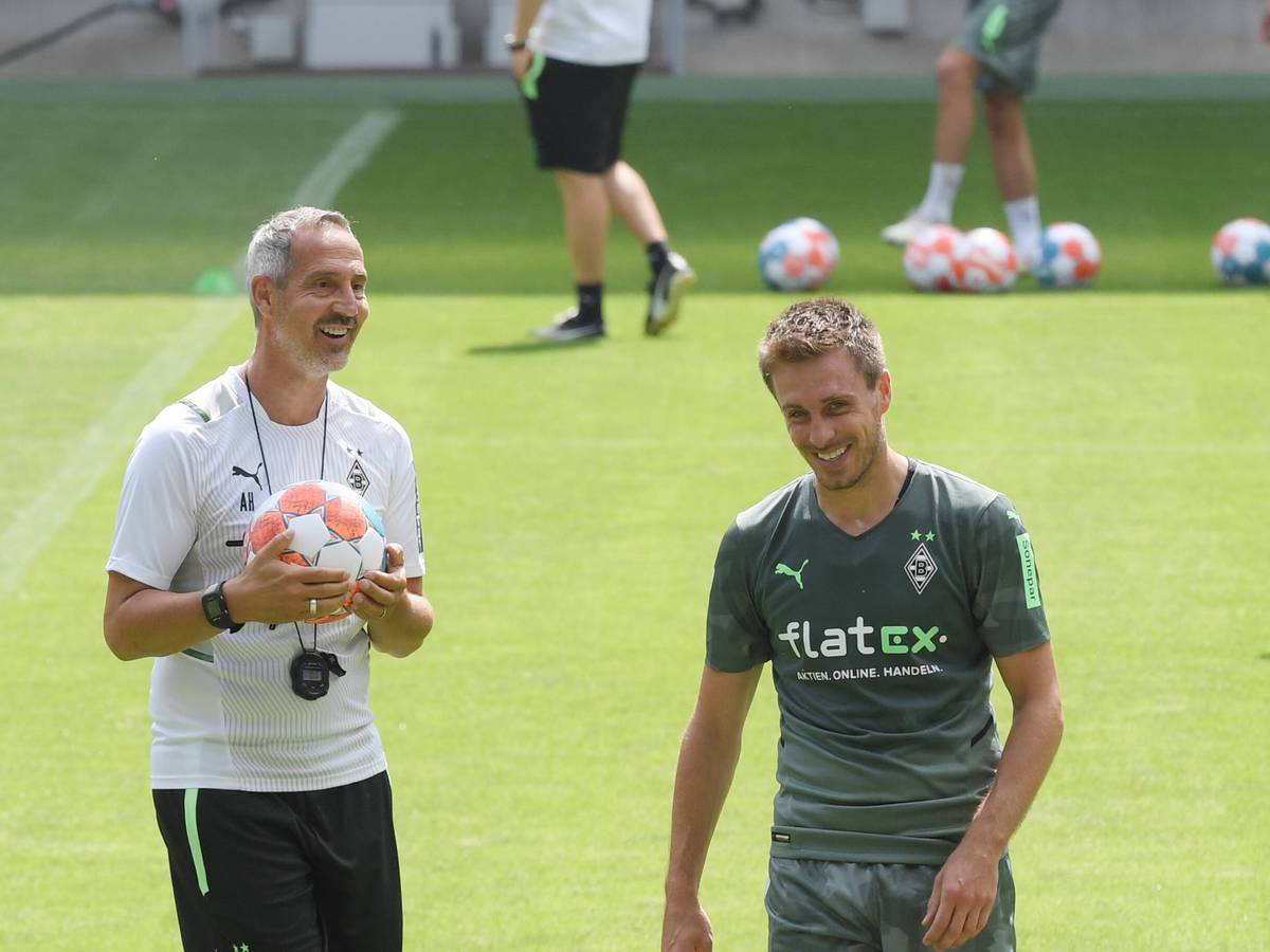 Adi Hütter (l.) mit einem Ball in der Hand und Patrick Herrmann (r.) lachen.