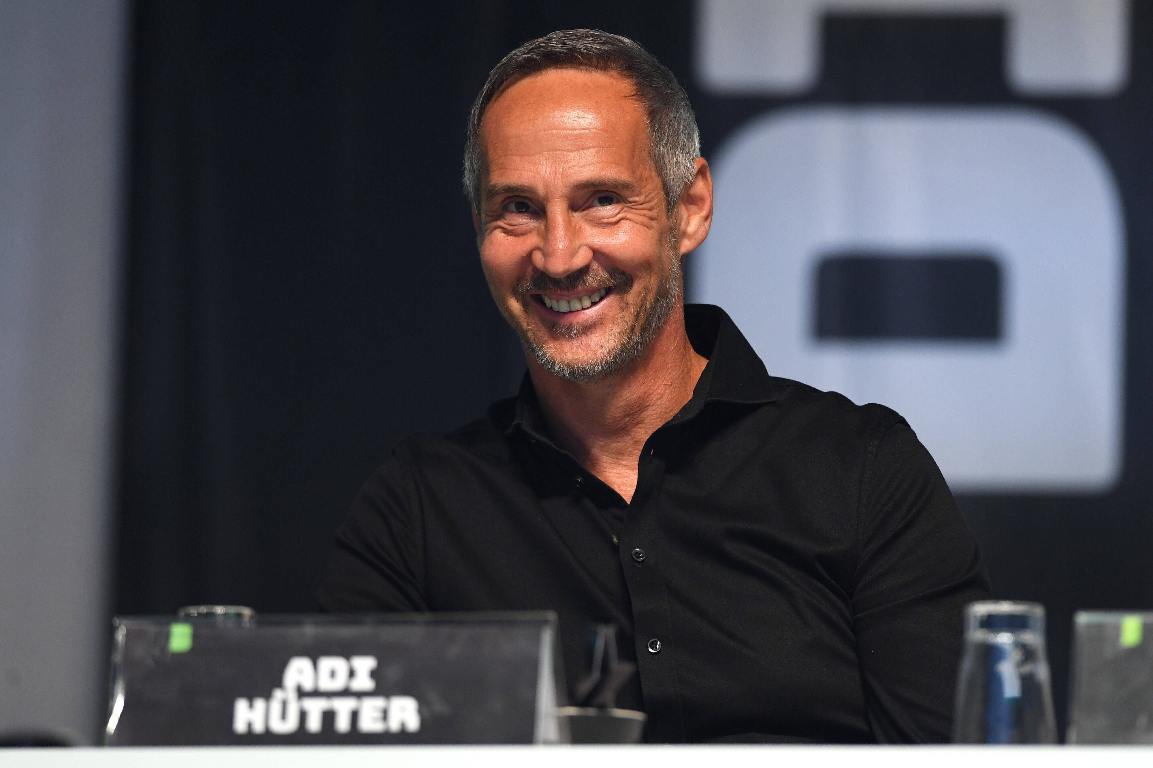 Adi Hütter sitzt auf einer Bühne im Borussia-Park. Gladbachs Trainer lächelt, er trägt ein schwarzes Hemd.