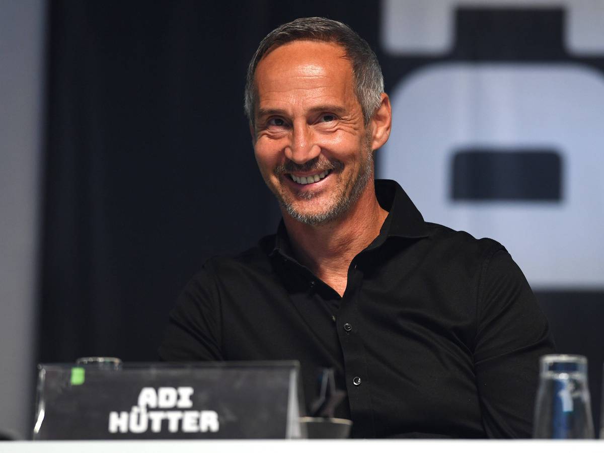 Adi Hütter sitzt auf einer Bühne im Borussia-Park. Gladbachs Trainer lächelt, er trägt ein schwarzes Hemd.