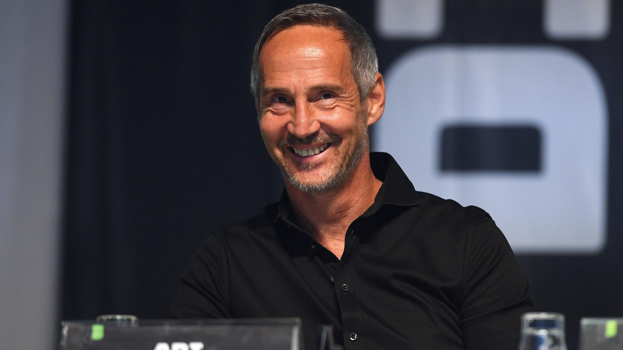 Adi Hütter sitzt auf einer Bühne im Borussia-Park. Gladbachs Trainer lächelt, er trägt ein schwarzes Hemd.
