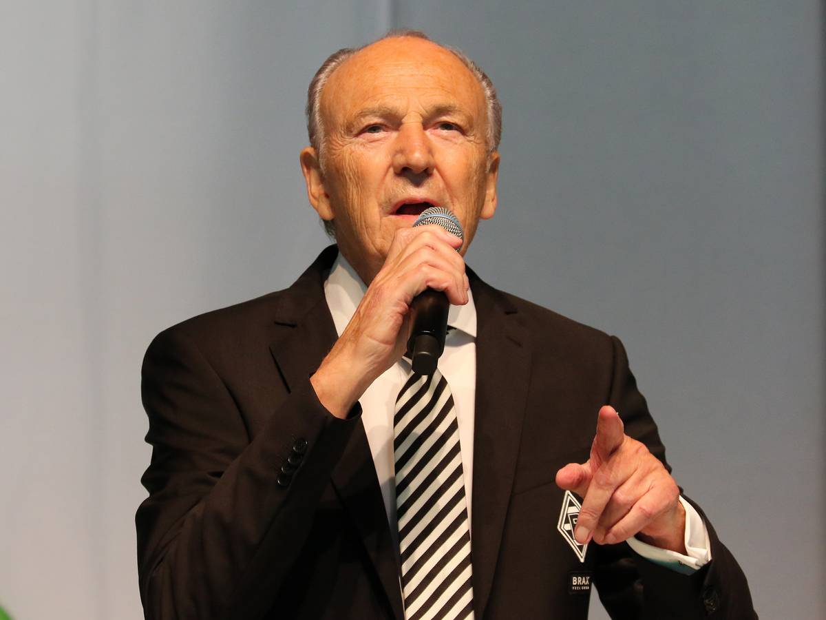 Borussias Präsident Rolf Königs bei der Mitgliederversammlung am 10. August 2021 im Gladbacher Stadion. Der 79-Jährige hält in der rechten Hand ein Mikro, mit der linken Hand deutet er in Richtung Zuhörer.