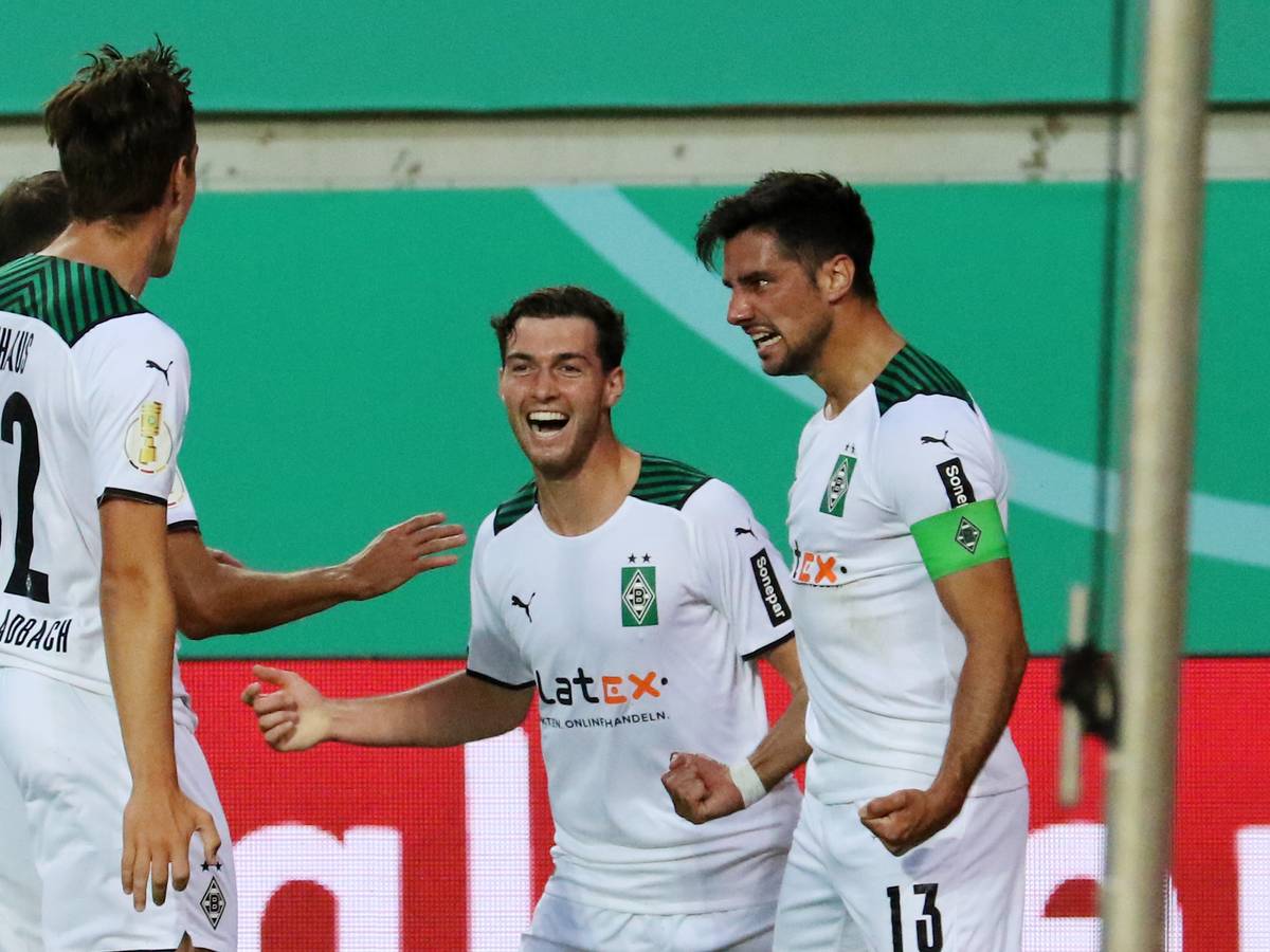 Die Gladbacher Florian Neuhaus und Joe Scally bejubeln gemeinsam mit Torschütze Lars Stindl das 1:0 in der 1. Runde des DFB-Pokals beim 1. FC Kaiserslautern am 9. August 2021.