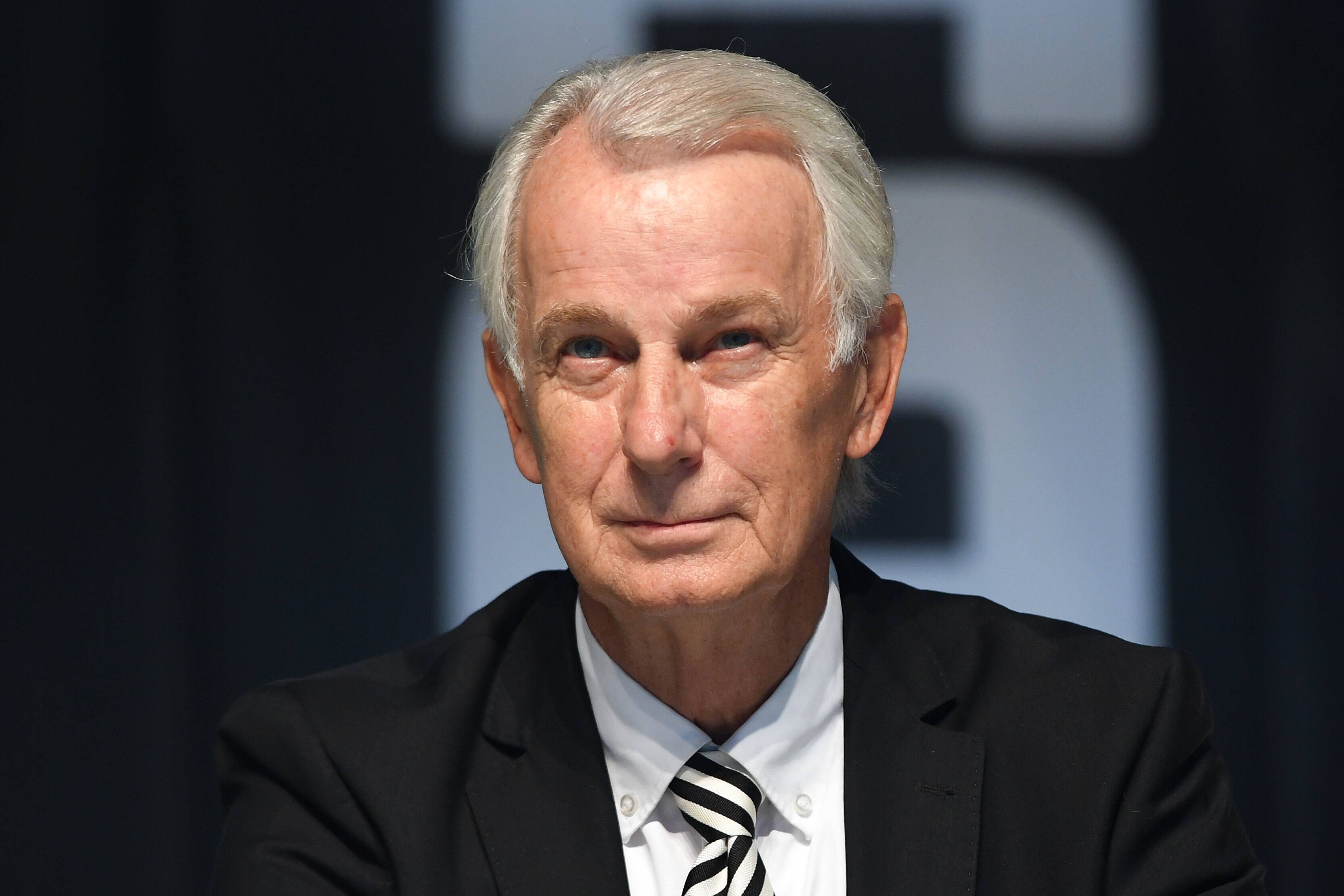 Gladbachs Vize-Präsident sitzt auf der Bühne im Borussia-Park und lächelt.
