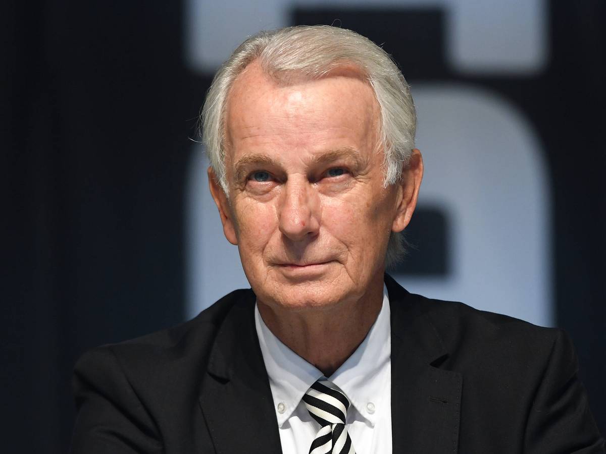 Gladbachs Vize-Präsident sitzt auf der Bühne im Borussia-Park und lächelt.