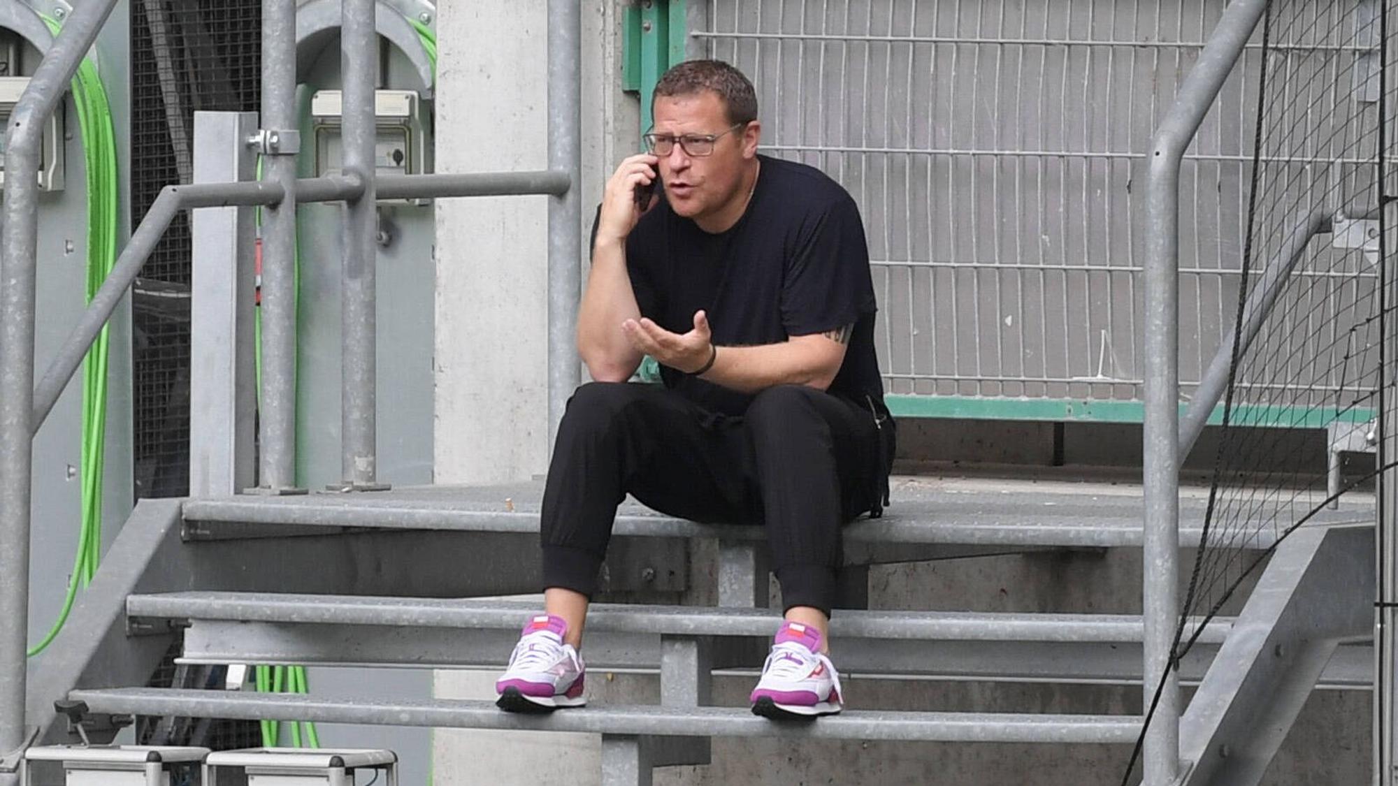 Gladbach-Manager Max Eberl sitzt auf einer Metalltreppe im Borussia-Park, derweil telefoniert er mit seinem Smartphone, mit der linken Hand gestikuliert er.