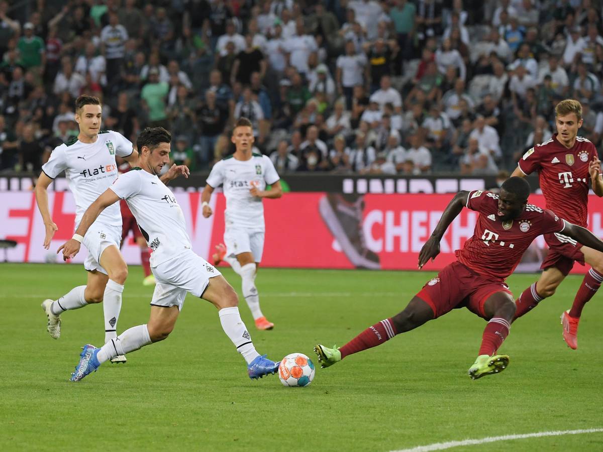 Gladbachs Lars Stindl (l.) beim Bundesliga-Eröffnungsspiel am 13. August 2021 im Zweikampf mit Bayerns Dayot Upamecano (r.).