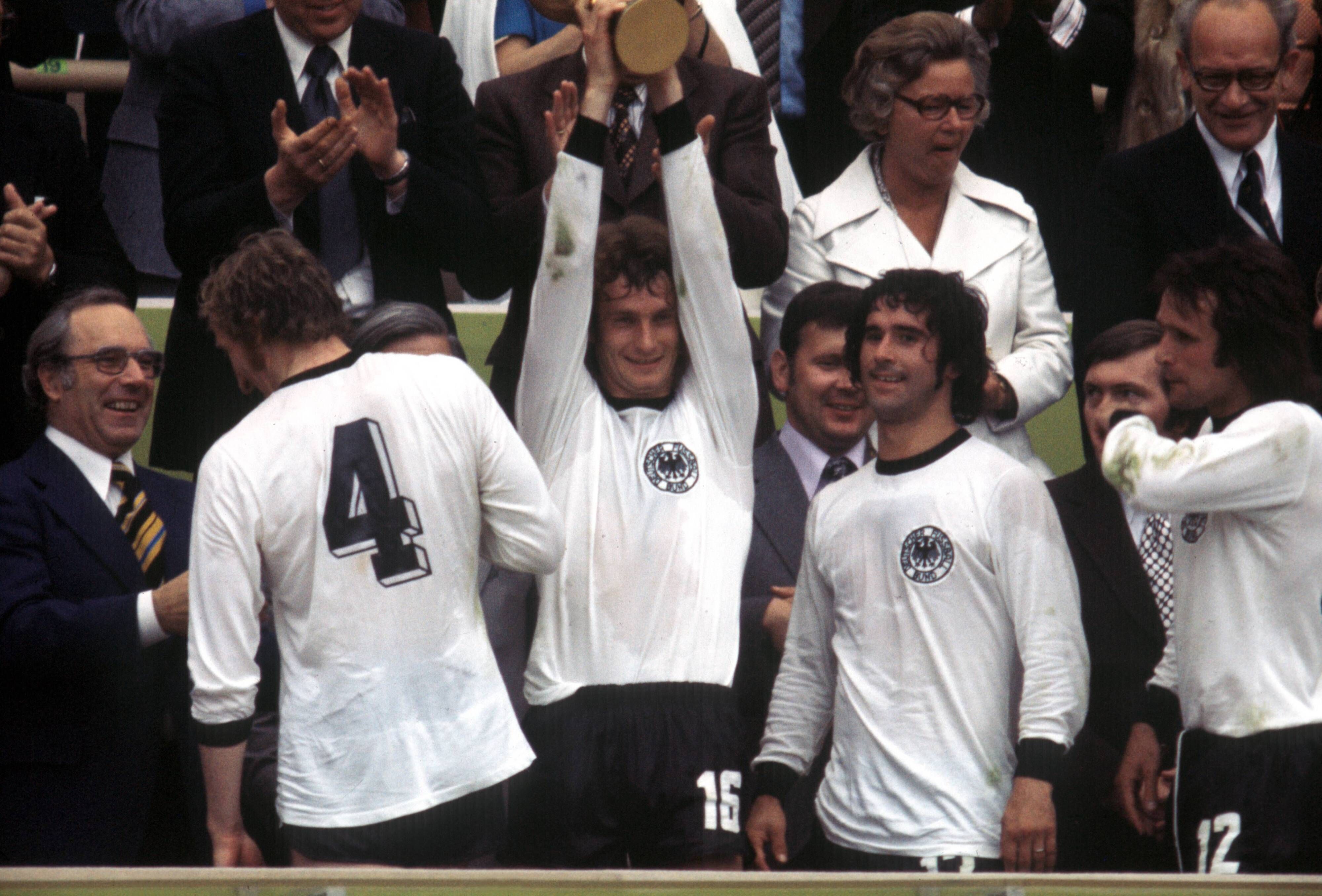 WM 1974, Siegerehrung Weltmeister BR Deutschland - Rainer Bonhof präsentiert den Pokal, daneben Hans Georg -Katsche- Schwarzenbeck, Gerd Müller und Wolfgang Overath

World Cup 1974 Award Ceremony World Champion BR Germany Rainer Bonhof presents the Cup next to it Hans Georg Katsche Schwarzenbeck Gerd Mueller and Wolfgang Overath
