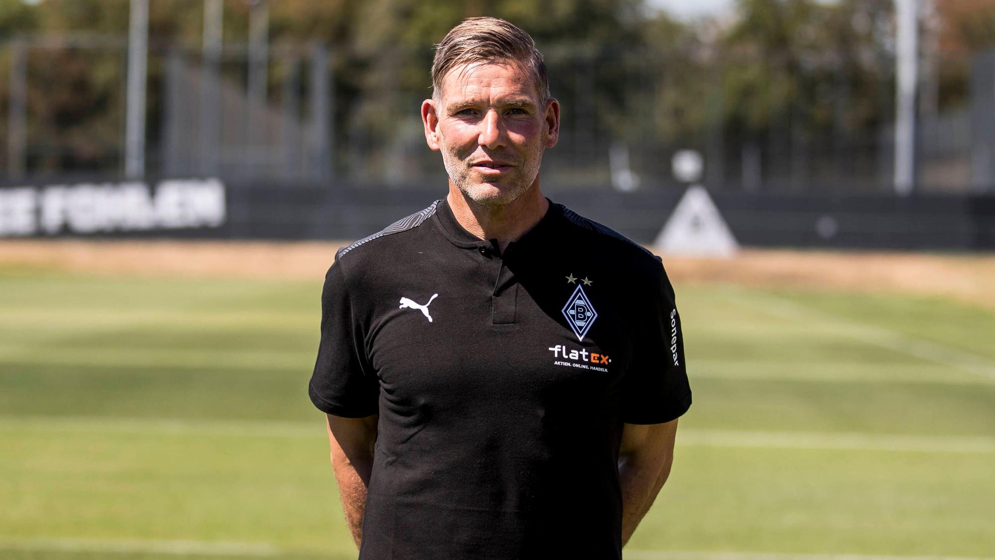 Gladbach-Legende und Torwarttrainer Uwe Kamps blickt in die Kamera, seine Arme hat er auf dem Rücken verschränkt.