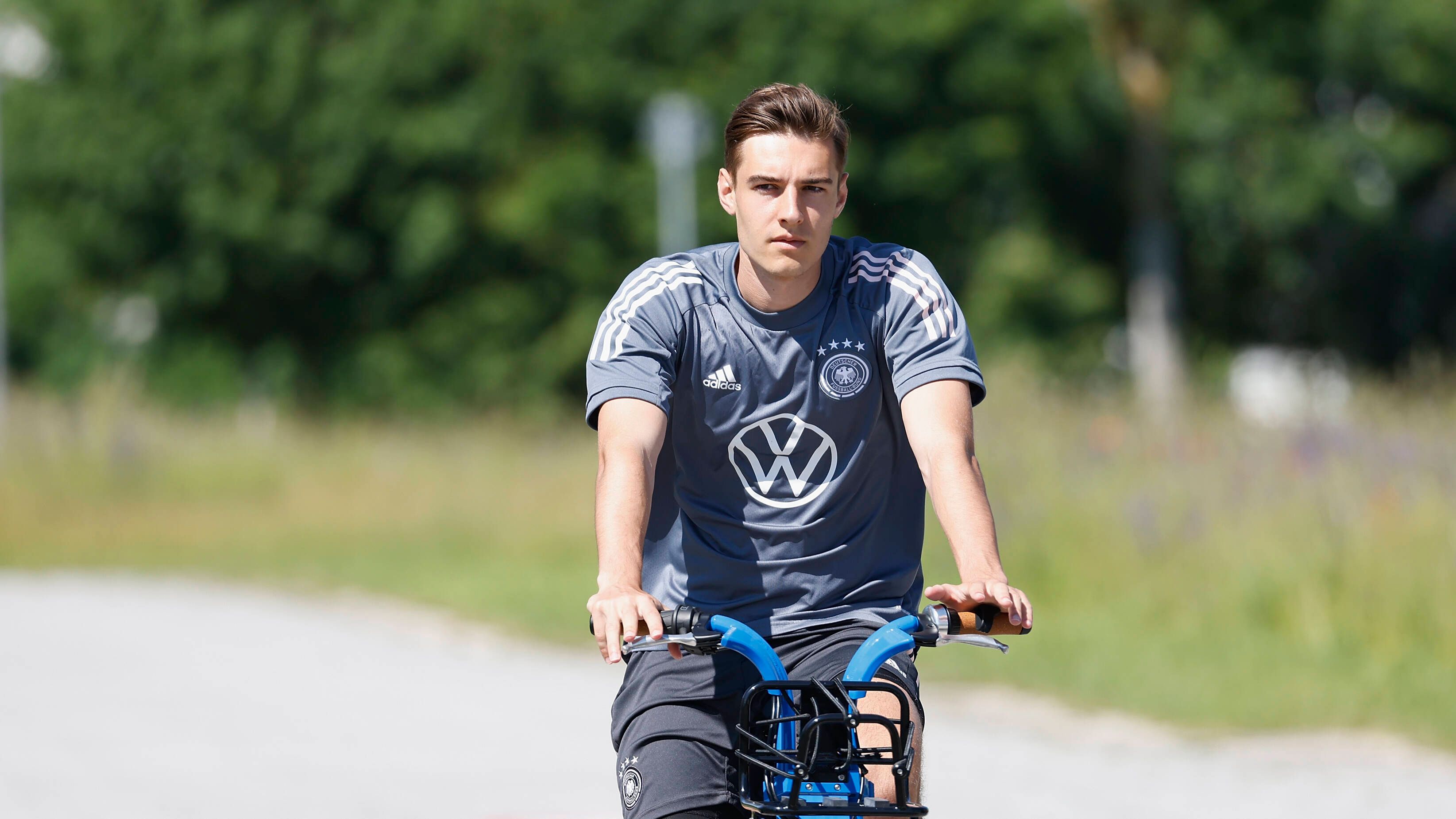 Gladbachs Nationalspieler Florian Neuhaus, hier zu sehen bei einer Radtour während des DFB-Trainingslagers in Herzogenaurach am 17. Juni 2021. Neuhaus sitzt auf einem Rand und schaut in die Kamera.