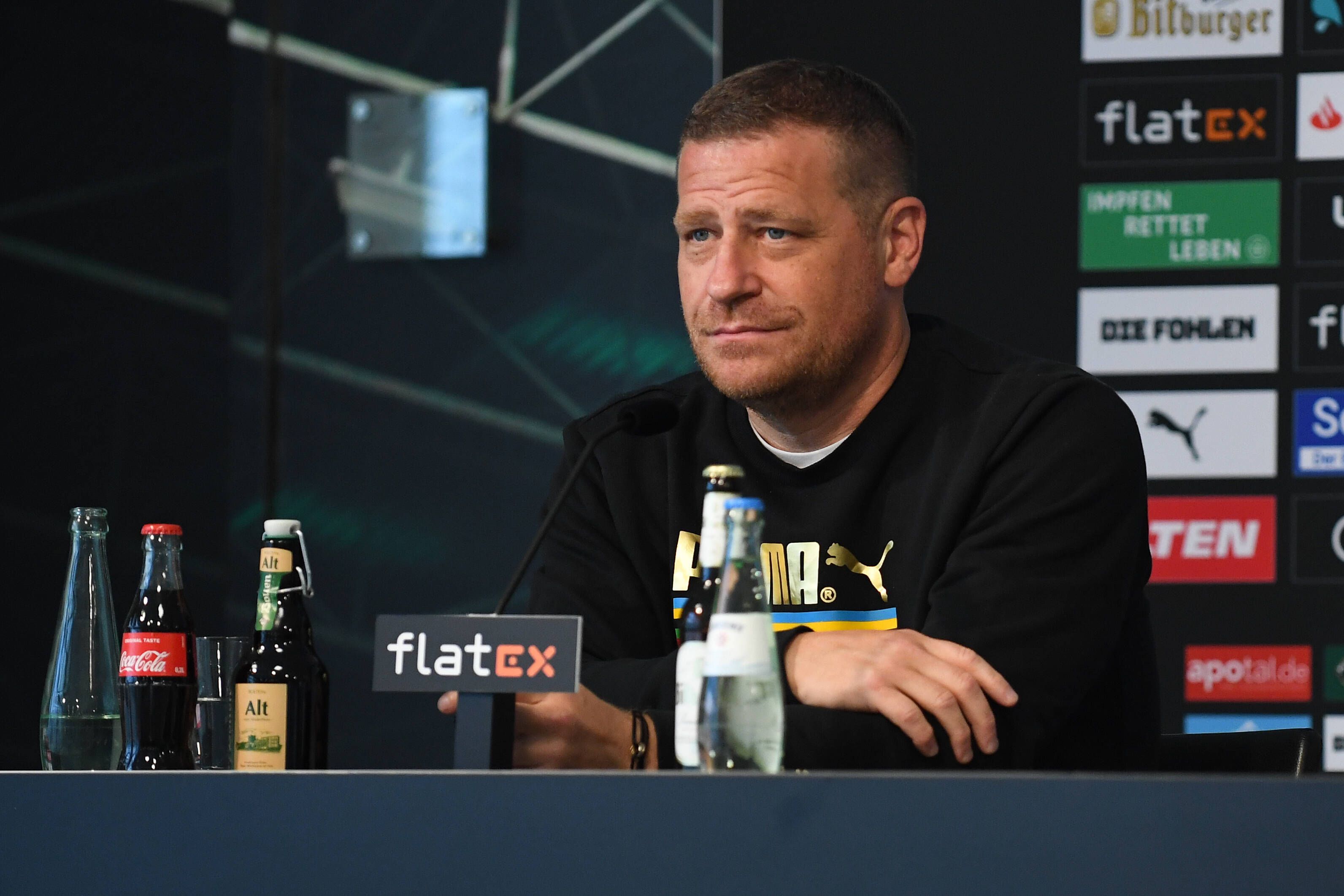 Gladbachs Sportdirektor Max Eberl lächelt mild auf der Pressekonferenz vor dem Auswärtsspiel zwischen Borussia Mönchengladbach und Union Berlin am 27. August 2021 im Borussia-Park am Podest sitzend.