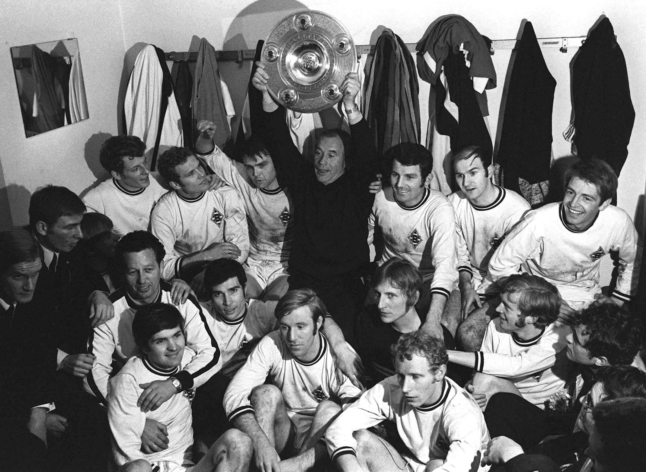 Trainer-Legende Hennes Weisweiler hält, umgeben von seiner Mannschaft, stolz die erste Gladbacher Meisterschale in die Höhe.