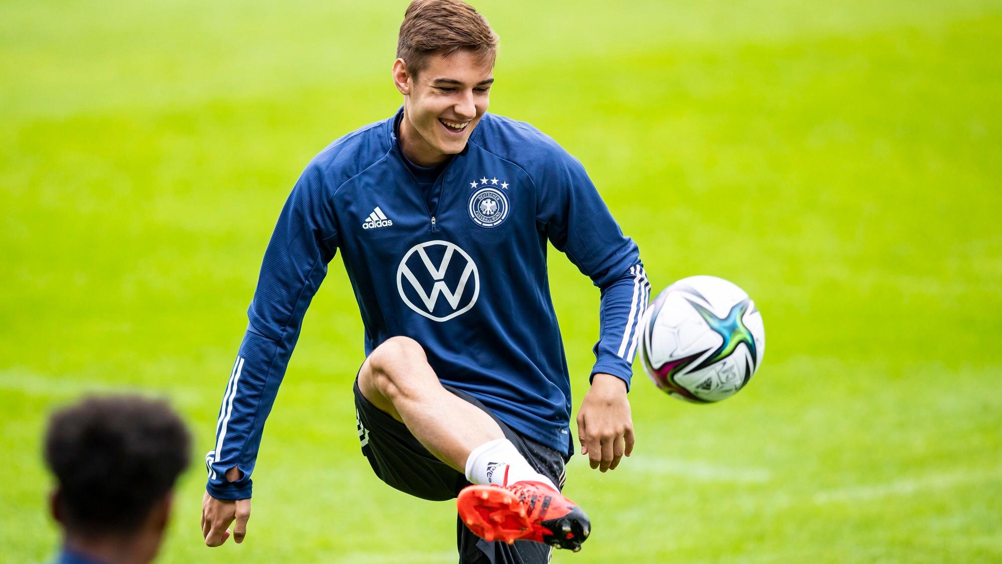 Gladbachs Florian Neuhaus jongliert bei einer Trainingseinheit der deutschen Nationalmannschaft am 31.08.2021in Stuttgart den Ball mit dem Fuß und lacht.