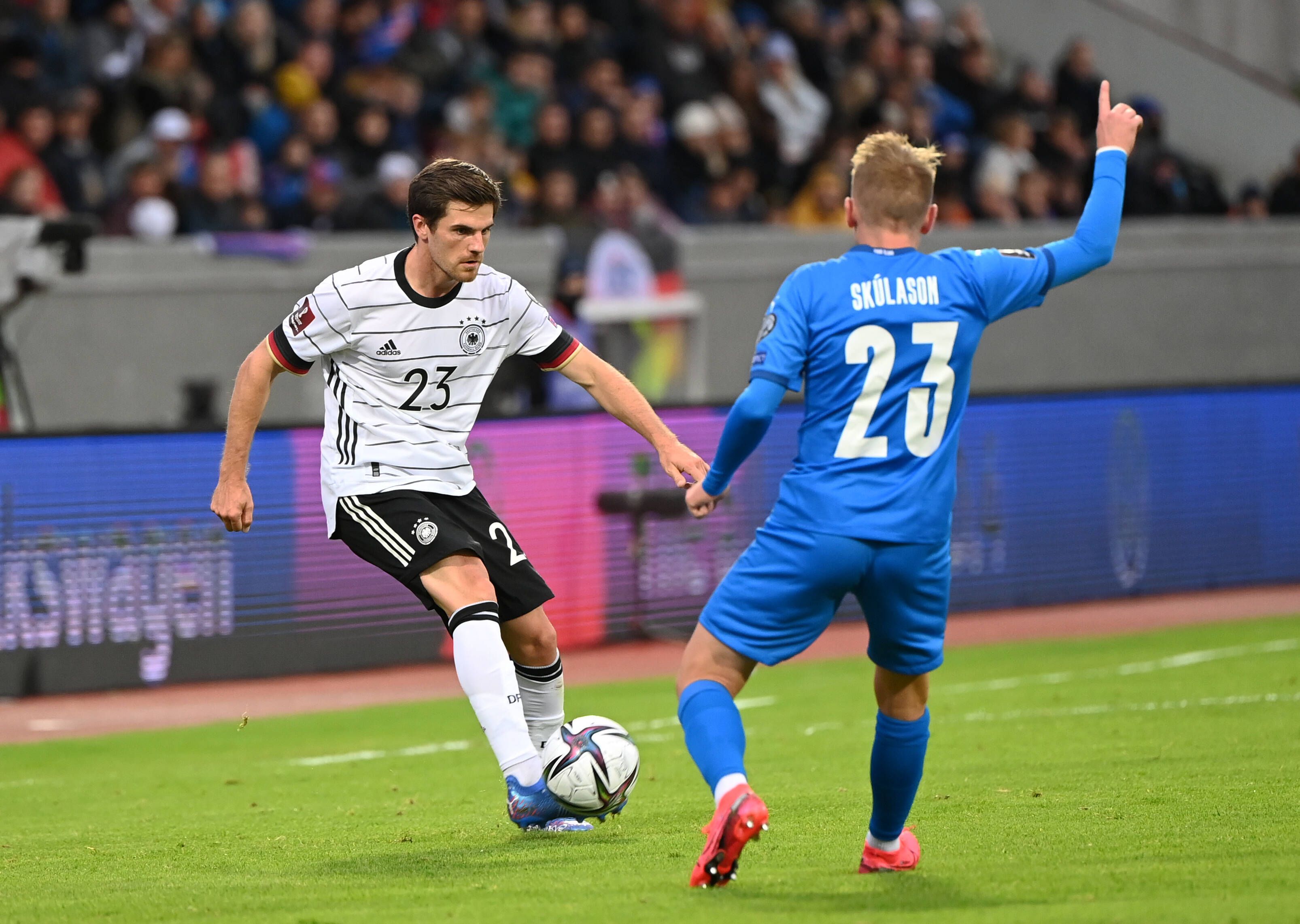 Gladbach-Profi Jonas Hofmann (l.). Auf diesem Foto ist das Fohlen im Trikot der DFB-Elf beim WM-Qualifikations-Duell am 8. September 2021 gegen Island in Reykjavik zu sehen. Hofmann spielt mit dem rechten Fuß den Ball, sein Gegenspieler hebt den rechten Arm.