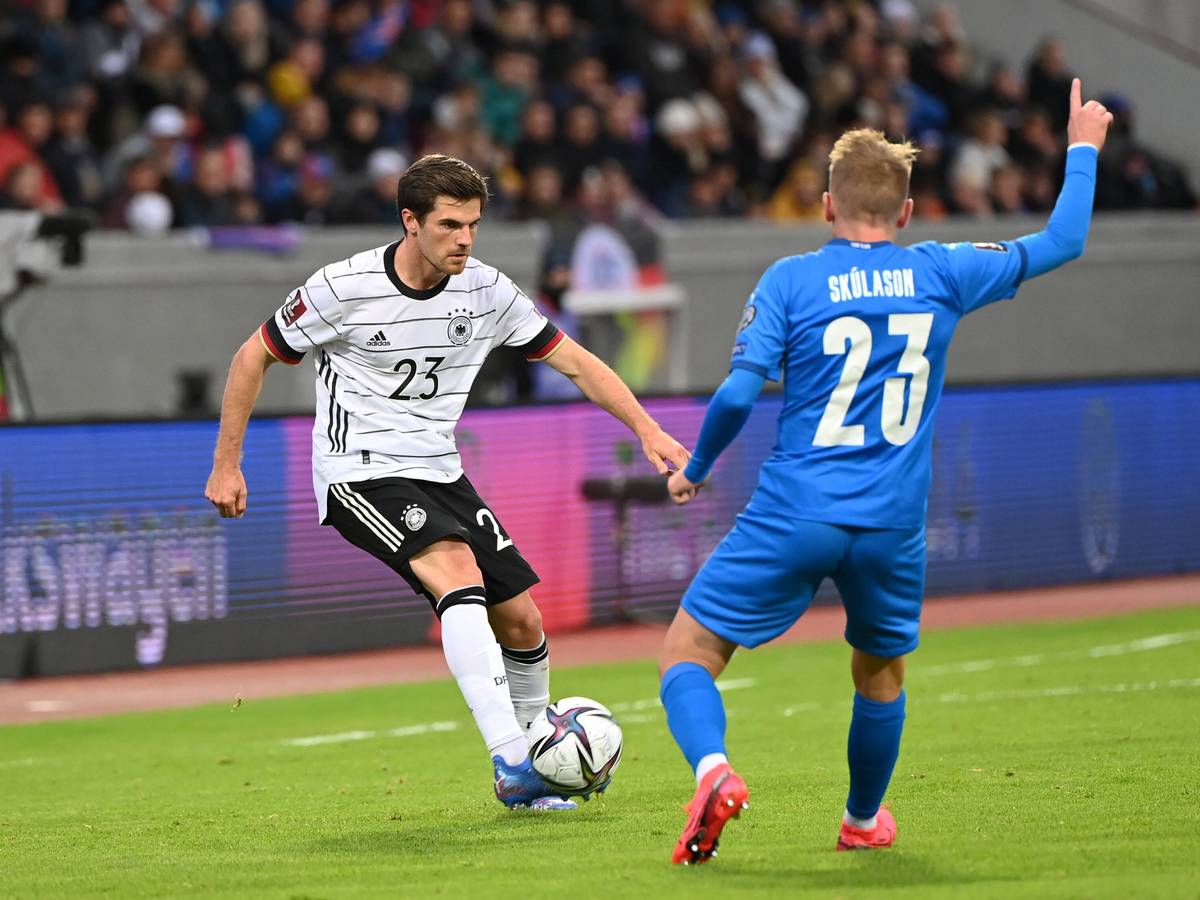 Gladbach-Profi Jonas Hofmann (l.). Auf diesem Foto ist das Fohlen im Trikot der DFB-Elf beim WM-Qualifikations-Duell am 8. September 2021 gegen Island in Reykjavik zu sehen. Hofmann spielt mit dem rechten Fuß den Ball, sein Gegenspieler hebt den rechten Arm.