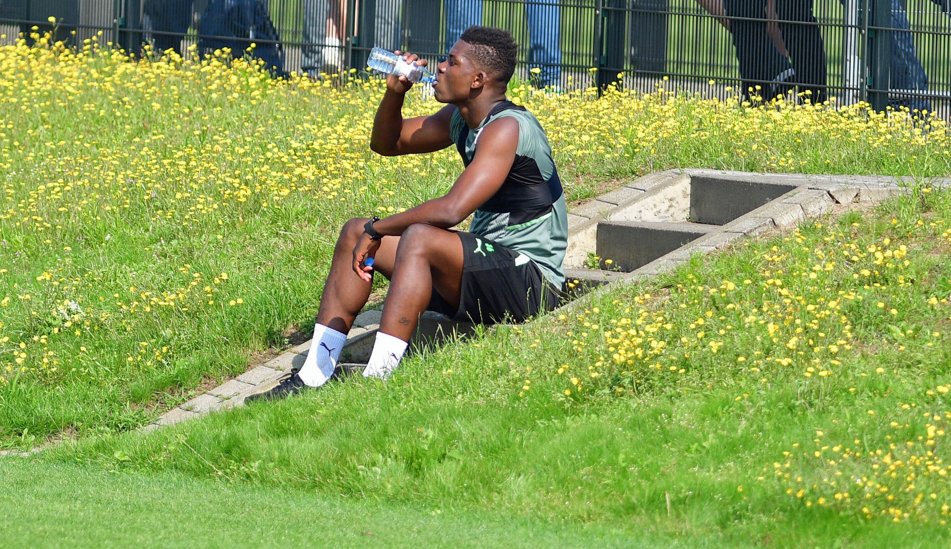 Gladbach-Stürmer Breel Embolo während einer Trinkpause bei einer Trainingseinheit der Fohlen am 4. August 2021 im Borussia-Park. Embolo sitzt auf einer Treppe am Spielfeldrand und nimmt einen Schluck aus einer Wasserflasche.